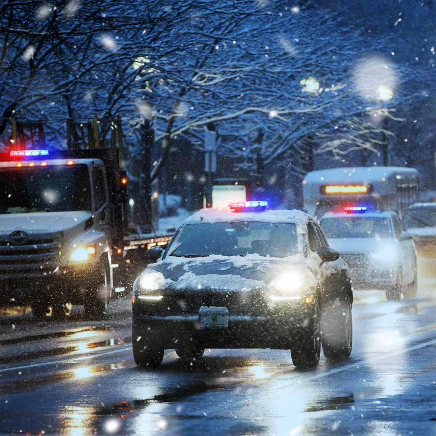 Verschneite Straßenszene. Polizeiautos mit Blinklichtern fahren auf nasser Straße. Schnee fällt, Bäume säumen die Straße im Hintergrund.