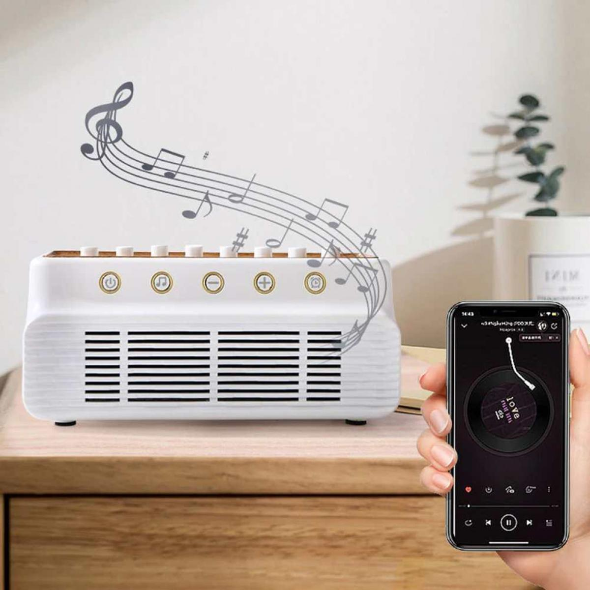 Ein weißer Lautsprecher mit Noten darüber. Ein Telefon zeigt Musiksteuerung. Holztisch und Pflanze im Hintergrund.