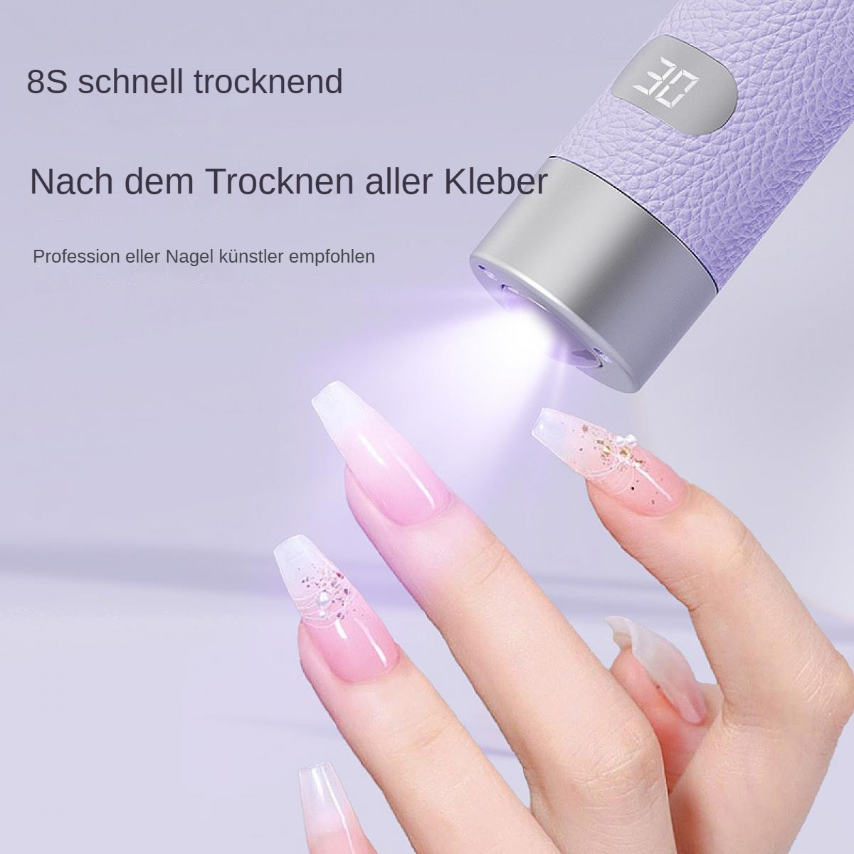 Ein Nageltrocknungswerkzeug mit Licht scheint auf eine Hand mit langen, verzierten Nägeln. Das Werkzeug zeigt eine Zahl.
