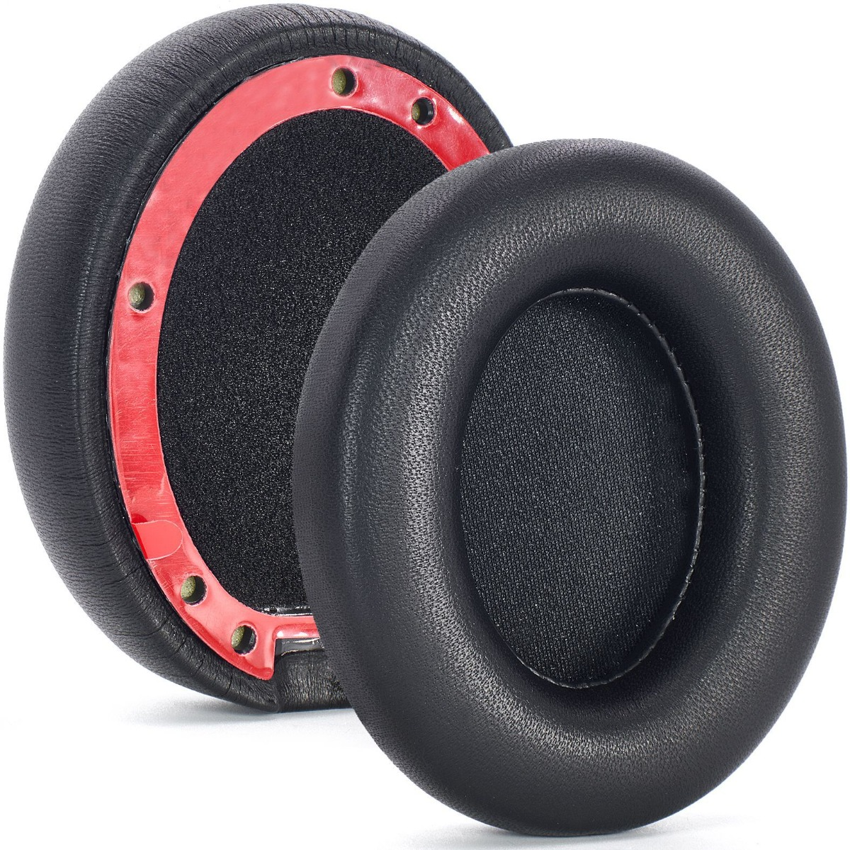 Dos almohadillas negras para auriculares. Una está parcialmente desmontada, mostrando un anillo rojo y espuma negra. La otra está entera.