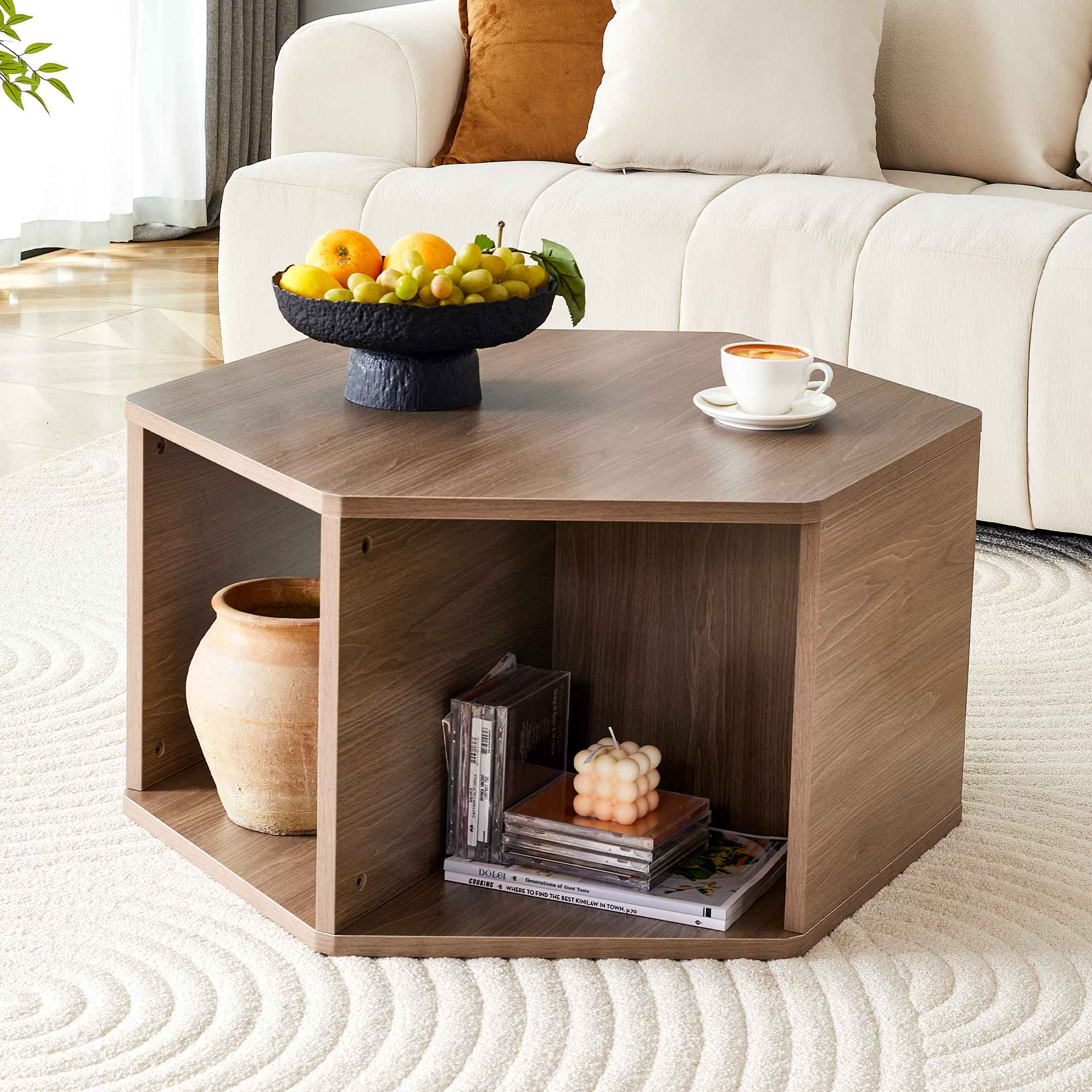 Ein sechseckiger Couchtisch aus Holz mit einer Obstschale, einer Kaffeetasse und Dekorationsartikeln. Im Hintergrund ein weißes Sofa.