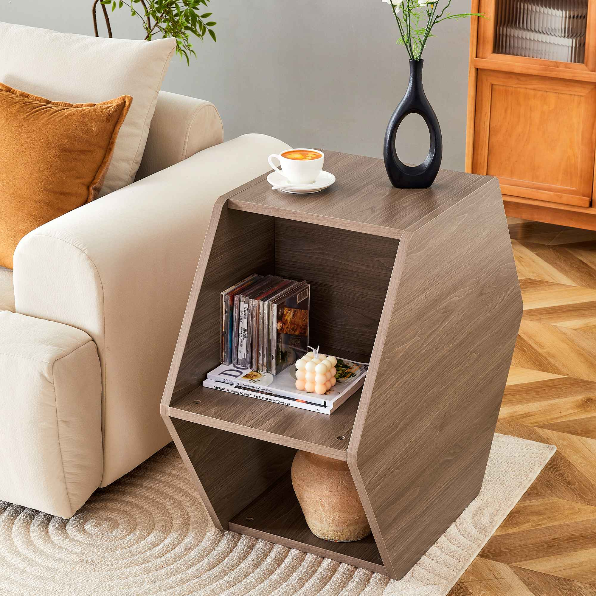 Ein moderner Beistelltisch mit Kaffeetasse, Vase und Büchern. Im Hintergrund sind ein Sofa und ein Holzschrank.