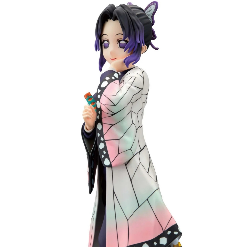 Figura de anime de una mujer con una túnica con estampado de mariposa, sosteniendo un objeto pequeño. Tiene el pelo morado y está sonriendo.