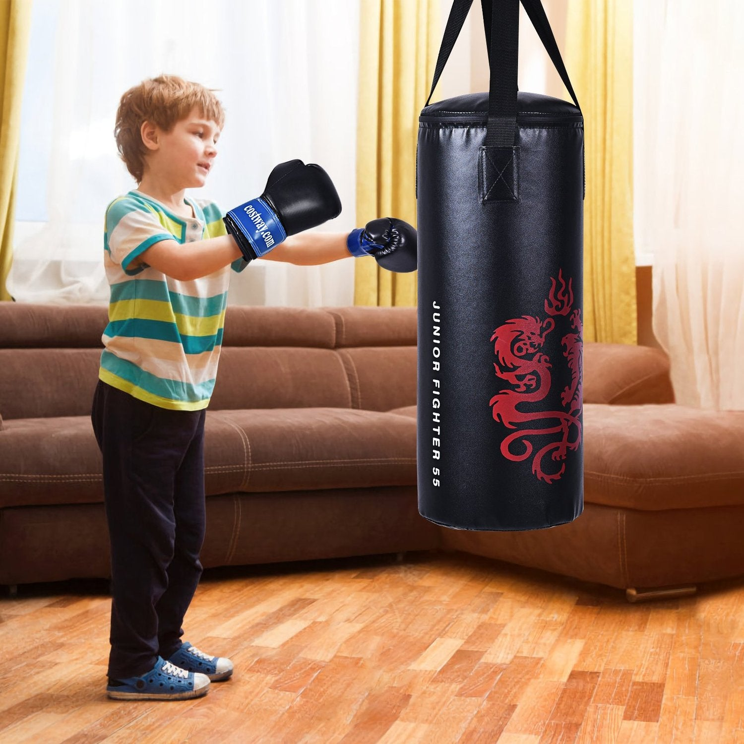 Un niño con guantes de boxeo golpea un saco de boxeo negro con un diseño de dragón rojo. Un sofá marrón está en el fondo.