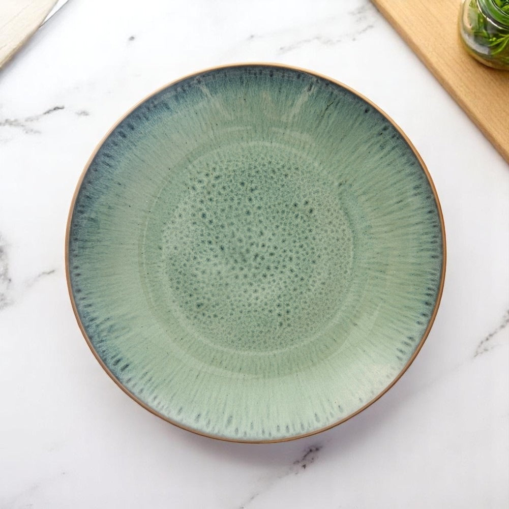 Vista cenital de un plato de cerámica verde con superficie texturizada. El plato está sobre una superficie de mármol blanco.