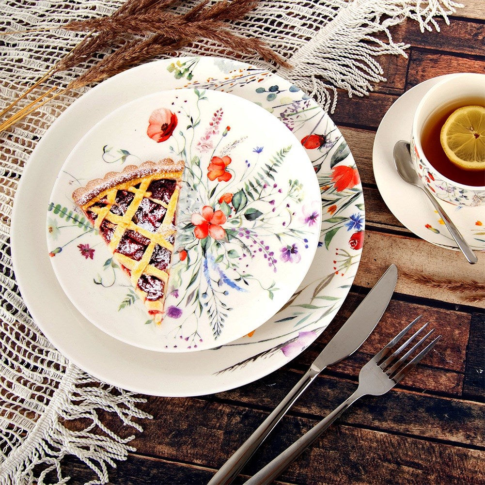 Una mesa con una porción de tarta en un plato floral, una taza de té y cubiertos. Fondo: mesa de madera y encaje.