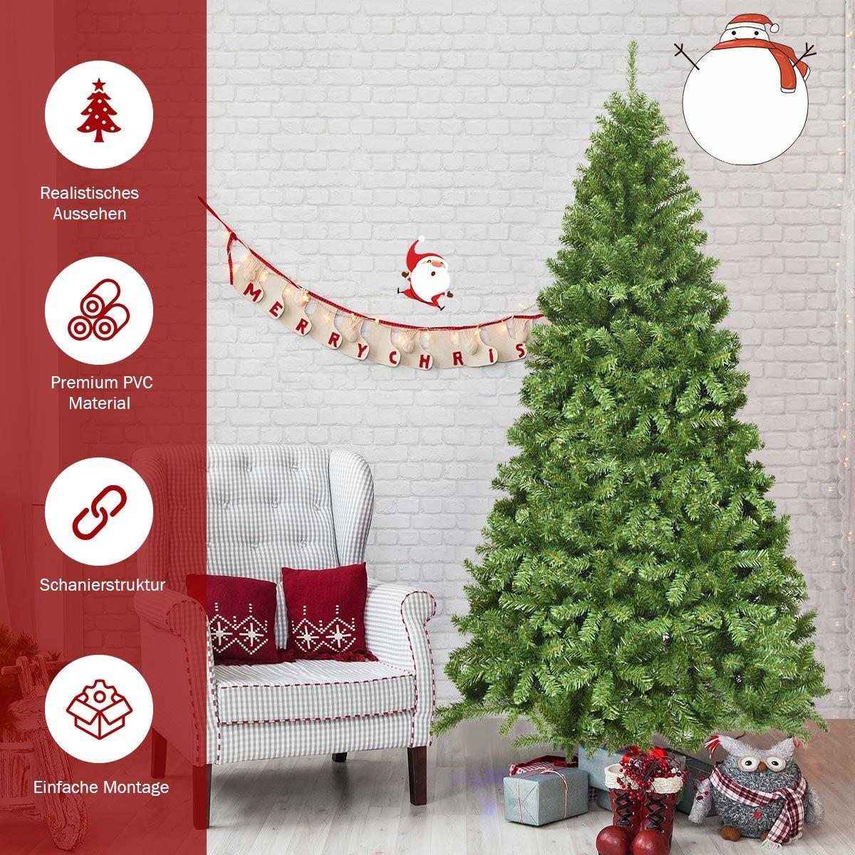 Un árbol de Navidad decorado está cerca de una silla con cojines rojos. Decoraciones de Papá Noel y muñeco de nieve en la pared.