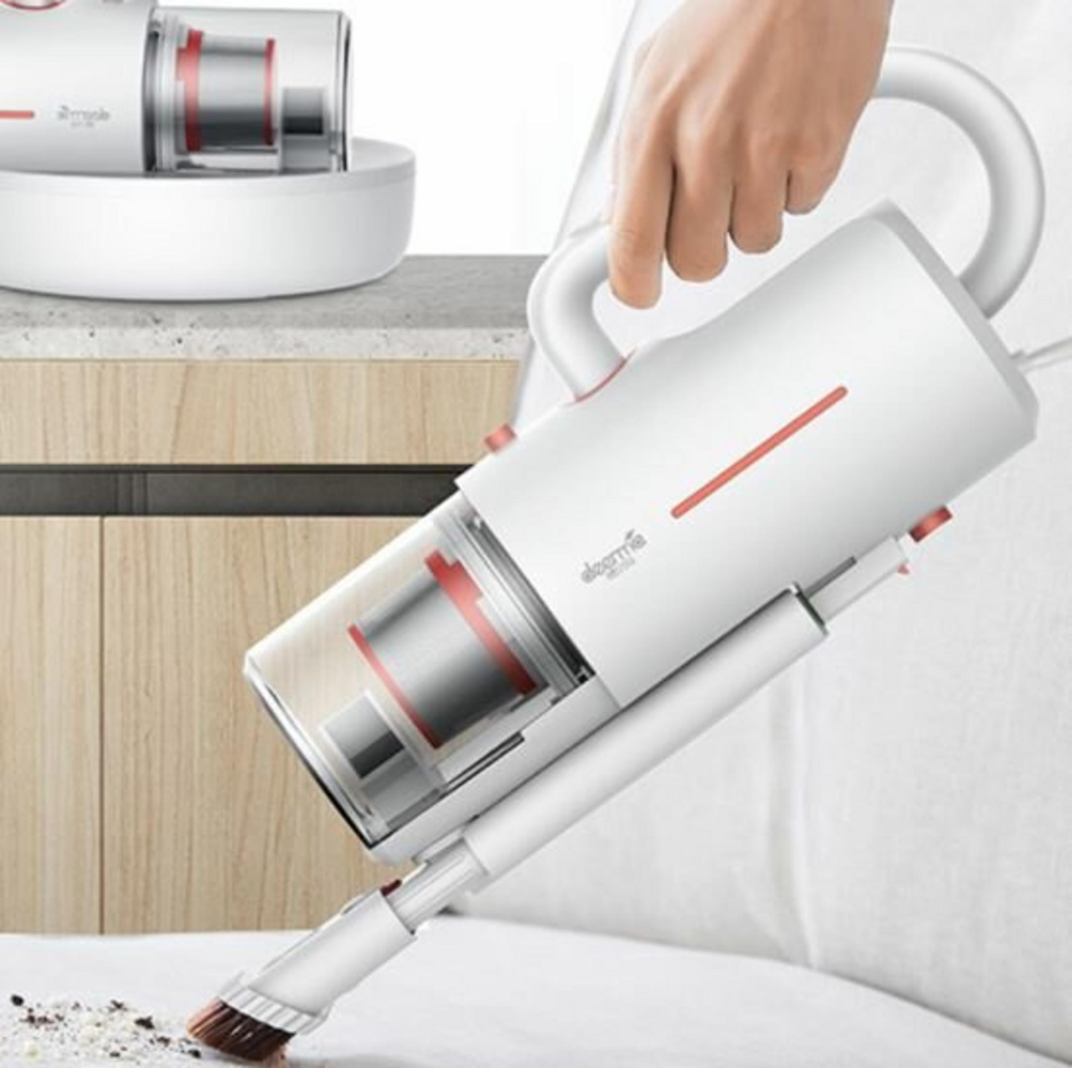 Biały odkurzacz ręczny jest trzymany przez dłoń. Szczotka czyści zanieczyszczenia z białej powierzchni. Drugi odkurzacz jest w tle.