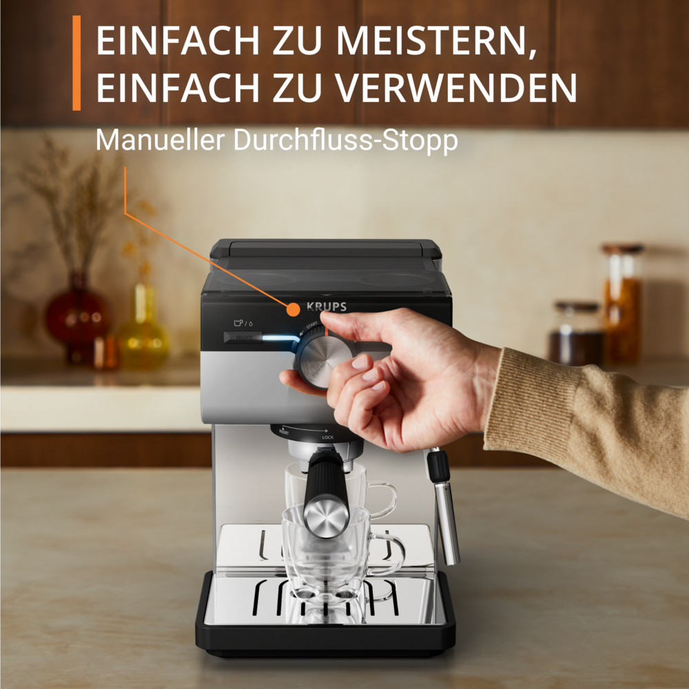 Eine Hand dreht das Einstellrad einer Krups Espressomaschine. Eine Glastasse steht unter dem Auslauf. Der Text lautet: 'Einfach zu meistern, einfach zu verwenden'.