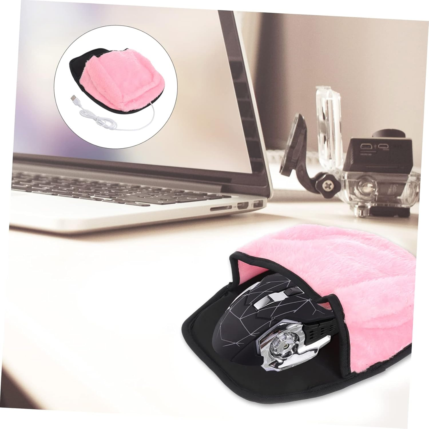 Eine Computermaus in einem rosa, flauschigen Wärmer auf einem Schreibtisch. Im Hintergrund ein Laptop und eine Kamera.