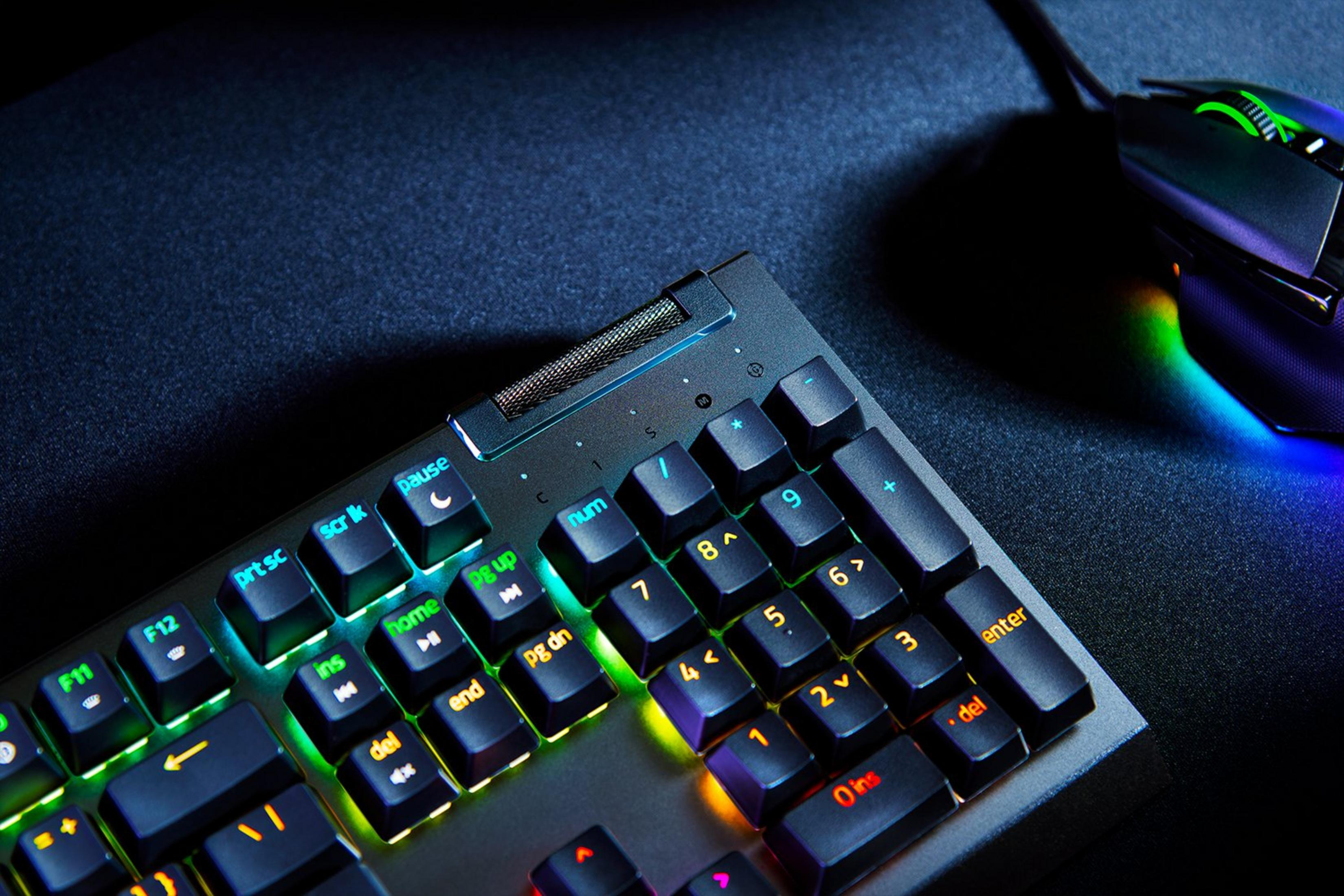 Un primo piano di tastiera e mouse. La tastiera ha tasti illuminati colorati. Il mouse è a destra.