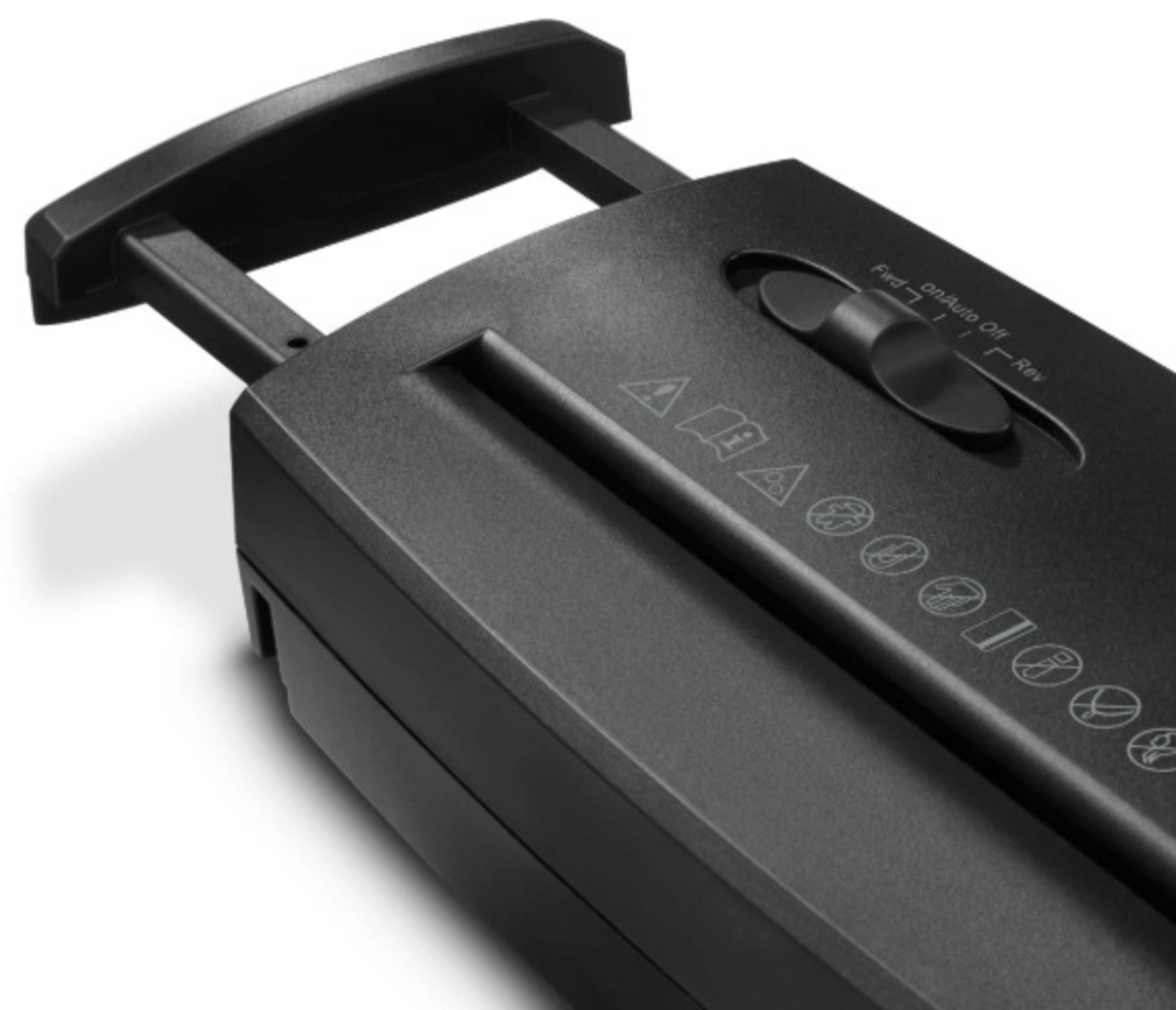 Zbliżenie czarnej niszczarki do papieru. Ma uchwyt, pokrętło i różne symbole bezpieczeństwa.