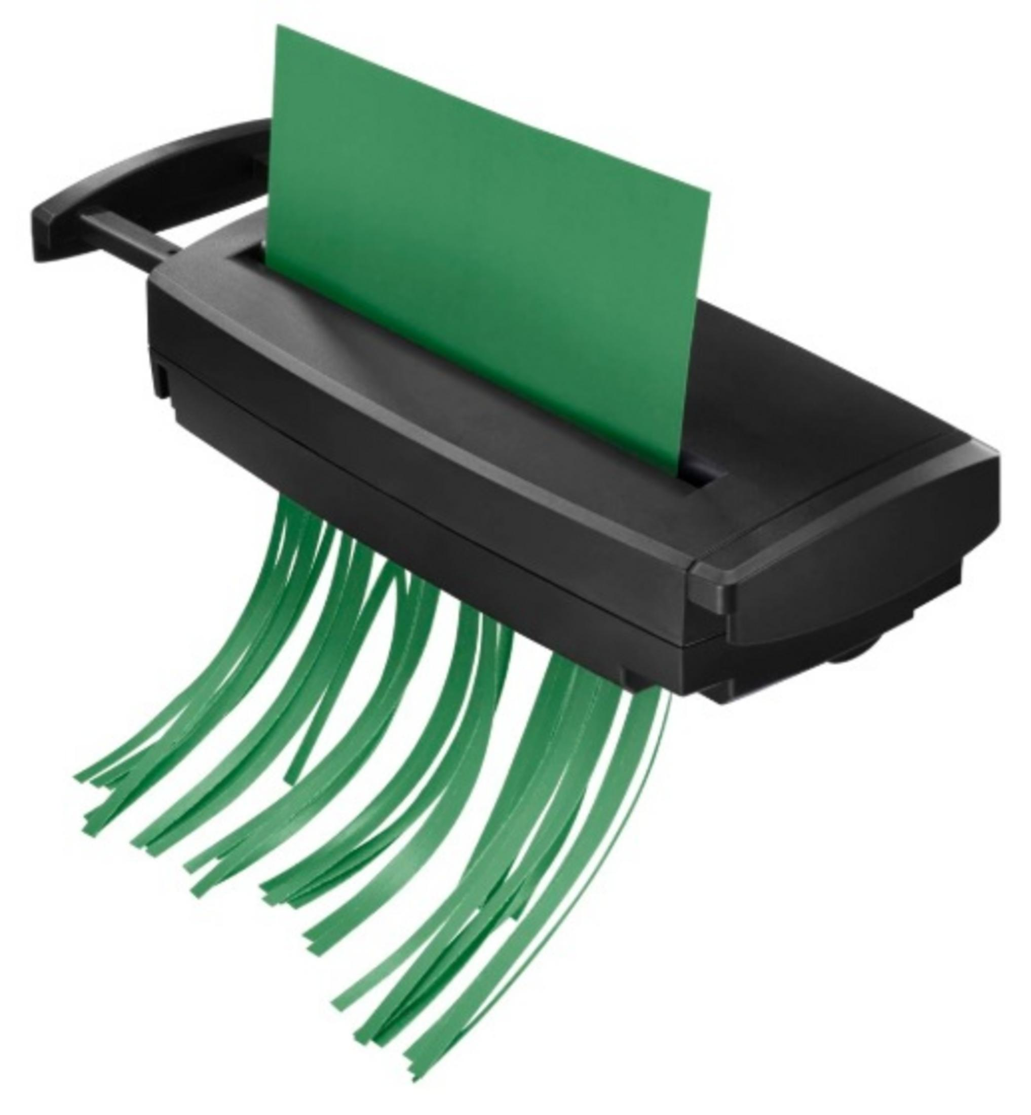 Czarna niszczarka tnie zieloną kartkę na cienkie paski. Pocięte paski opadają.