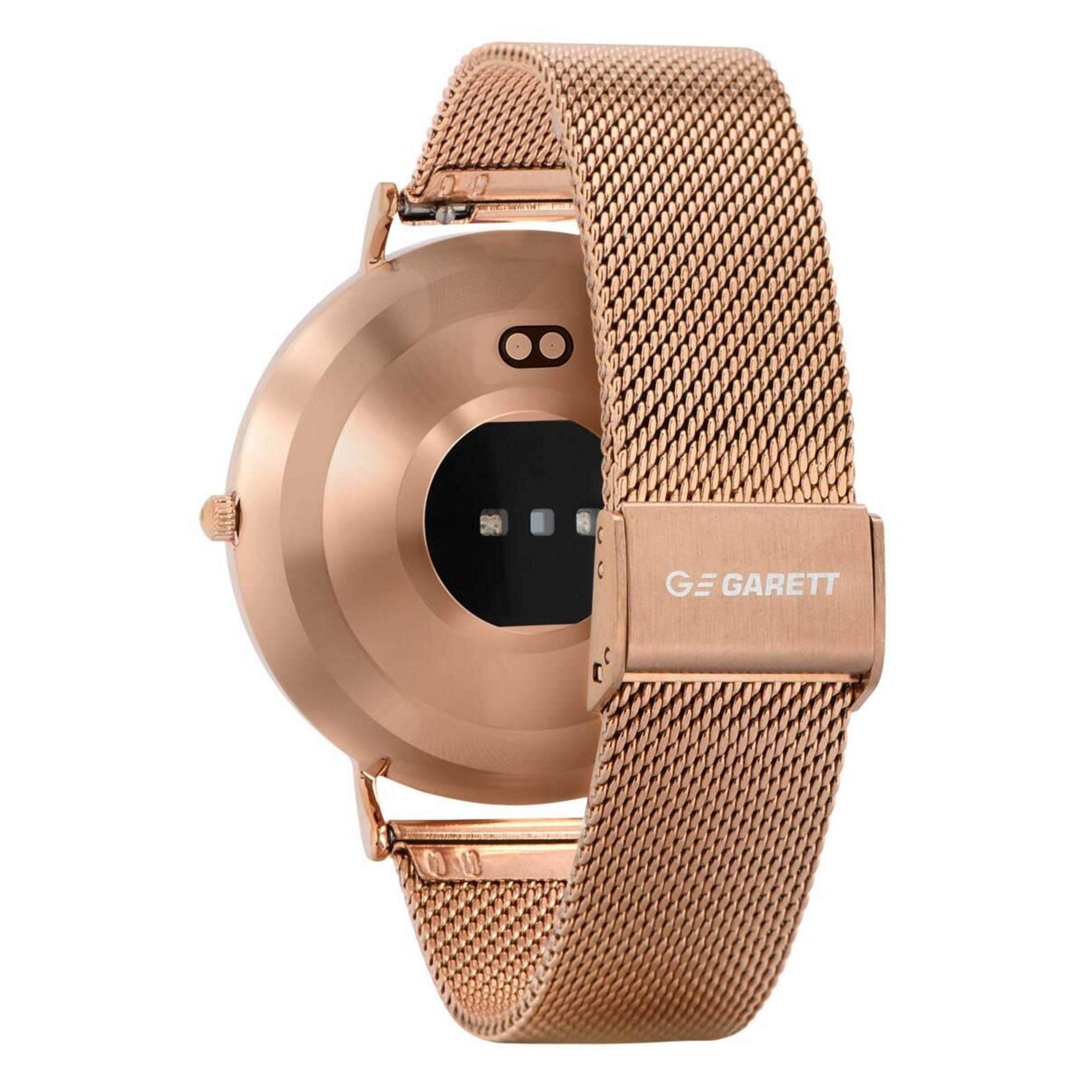 Une smartwatch or rose avec un bracelet en maille est affichée. Le cadran est rond et possède un intérieur noir avec des capteurs.