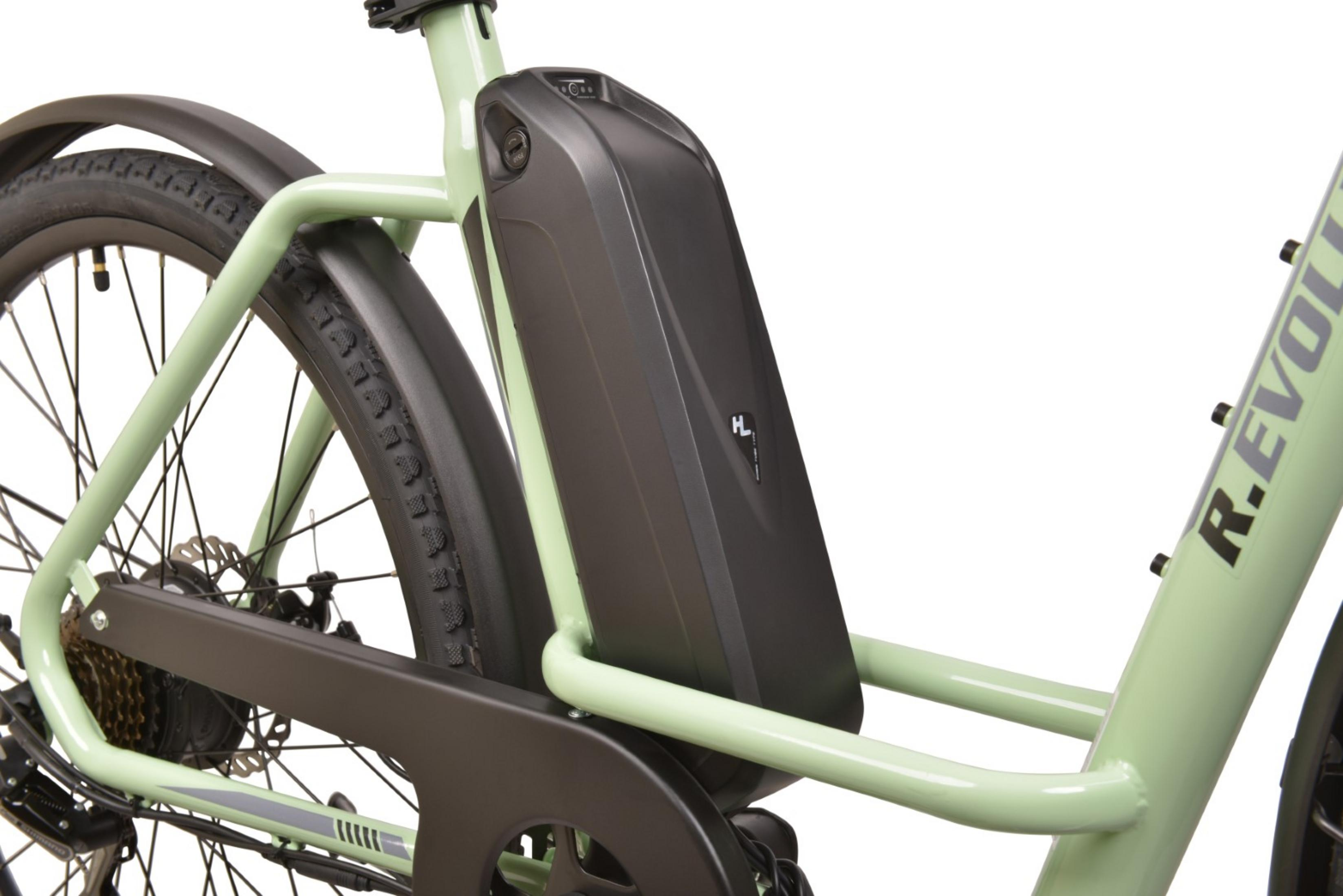 Zbliżenie zielonego roweru elektrycznego. Czarna bateria zamontowana na ramie. Widoczne opona i błotnik.