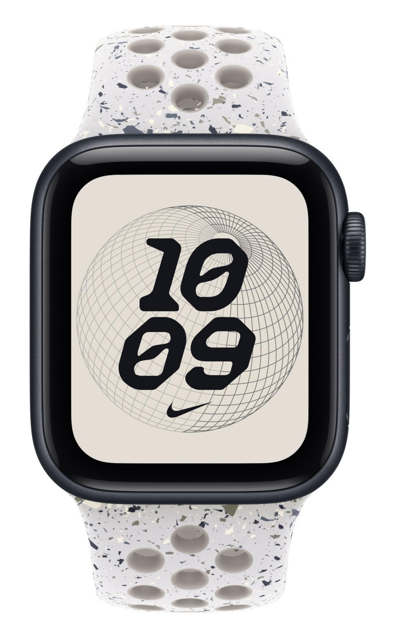 Primo piano di un Apple Watch nero con cinturino bianco maculato. Il quadrante mostra l'ora '10:09' su un grafico del globo e un logo Nike.