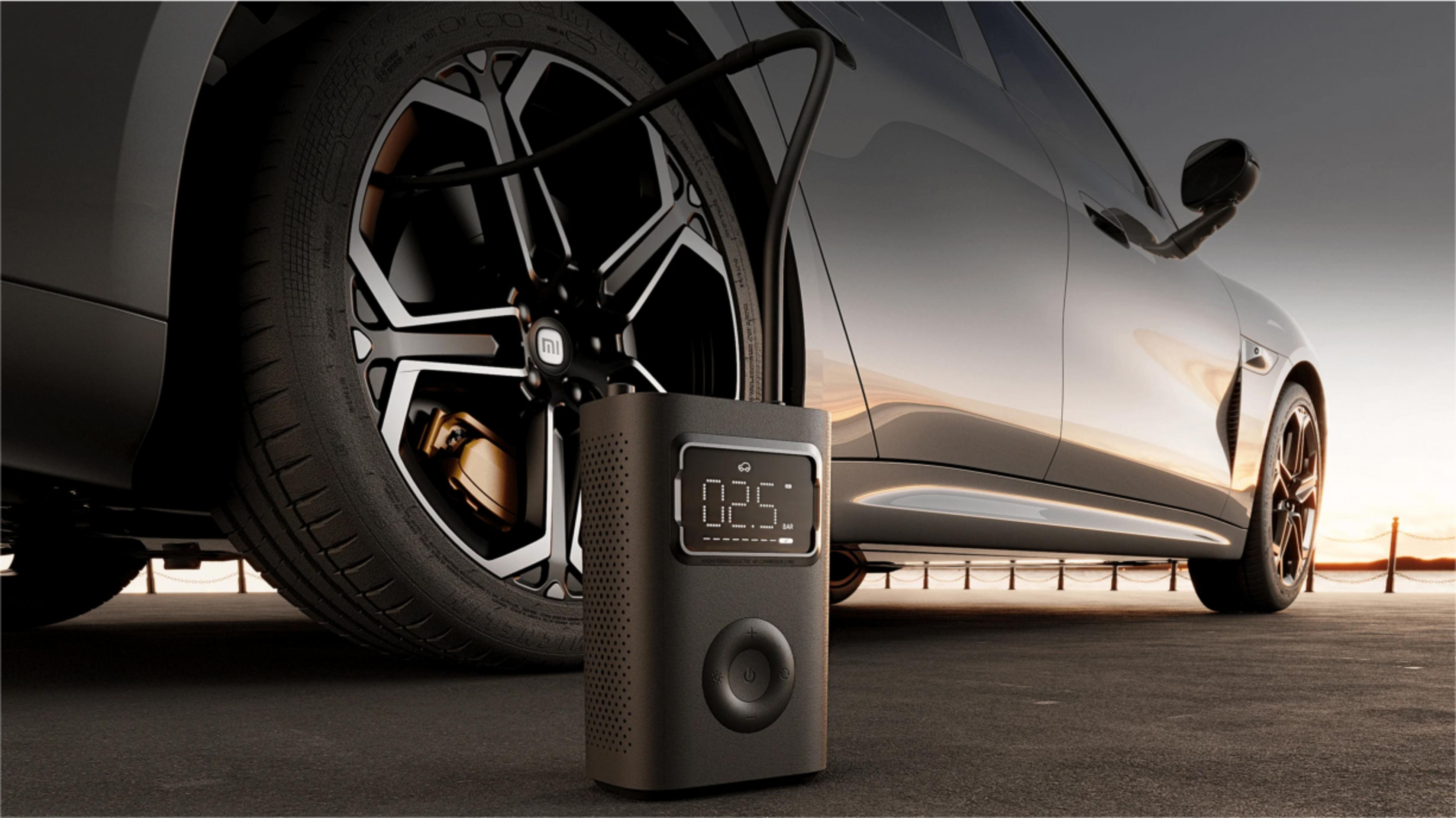 Ein schwarzer Autoreifen wird von einer kleinen schwarzen Luftpumpe aufgepumpt. Die Pumpe zeigt 02.5 an. Das Auto ist schlank und modern.