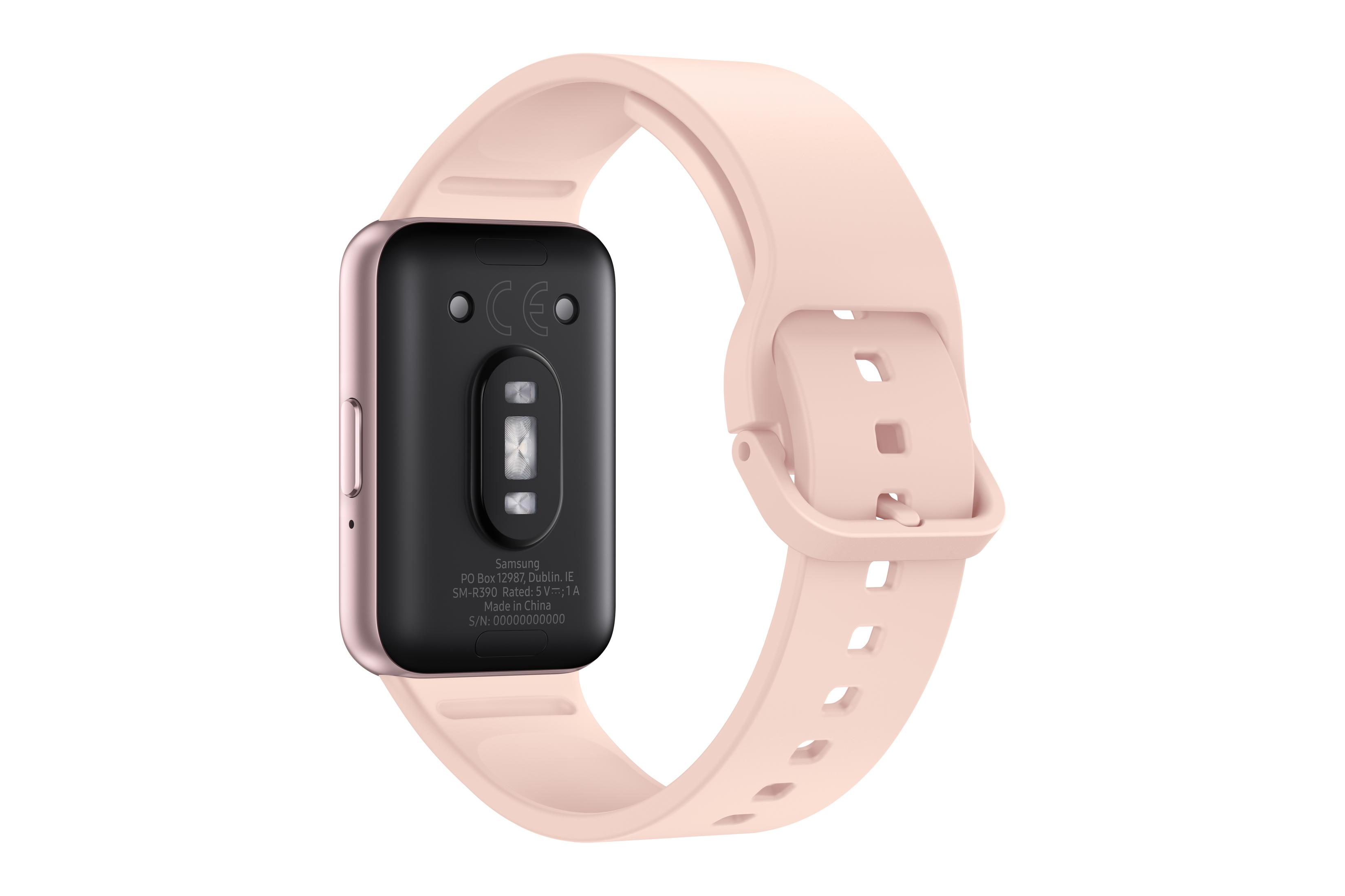 Een roségouden smartwatch met een lichtroze band wordt getoond op een witte achtergrond. De achterkant heeft tekst.