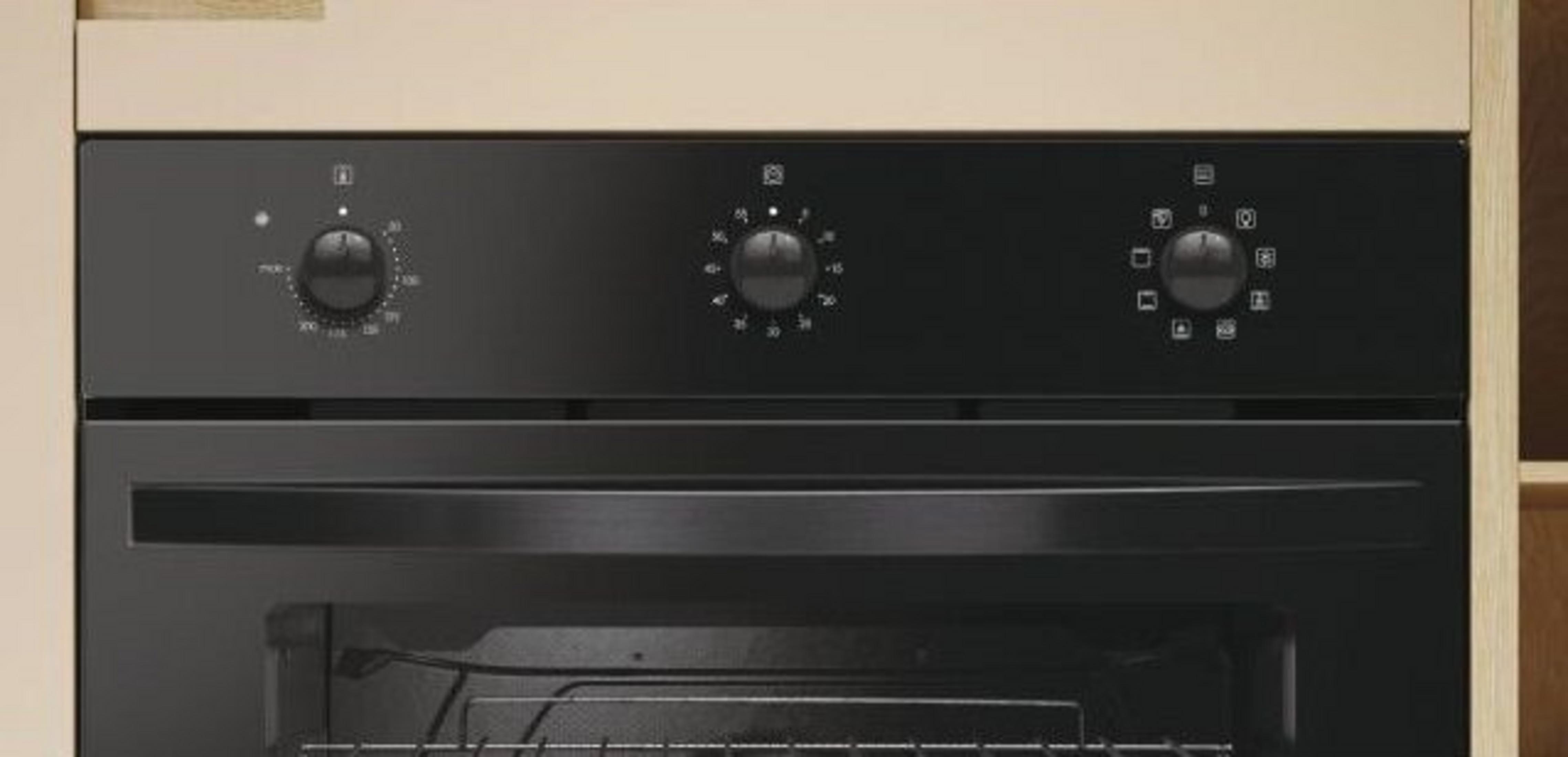Primo piano di un forno nero. Ha tre manopole, una porta e una griglia metallica. Un mobile beige lo circonda.