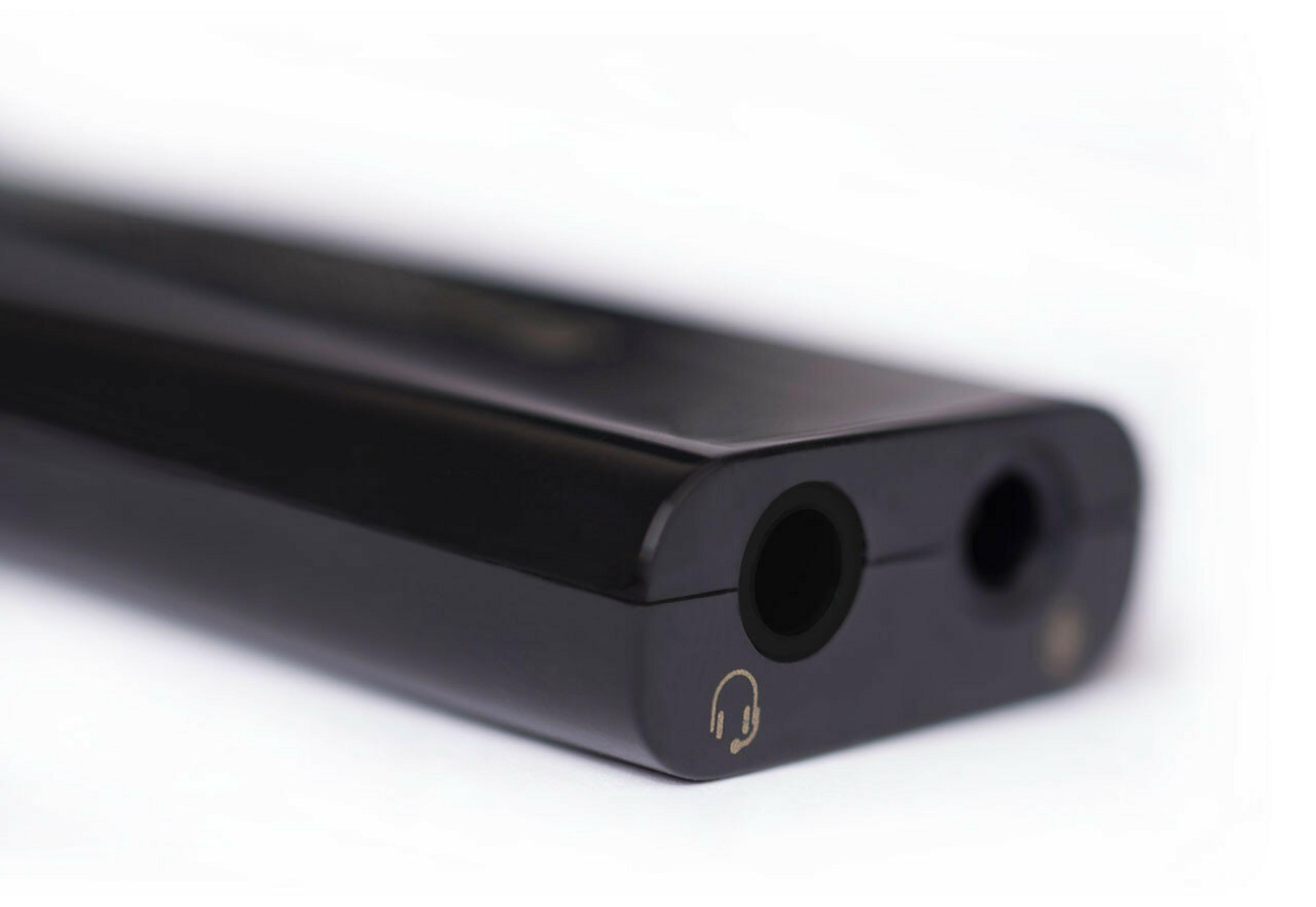 Primer plano de un dispositivo de audio negro con dos entradas. Un símbolo de auriculares es visible.