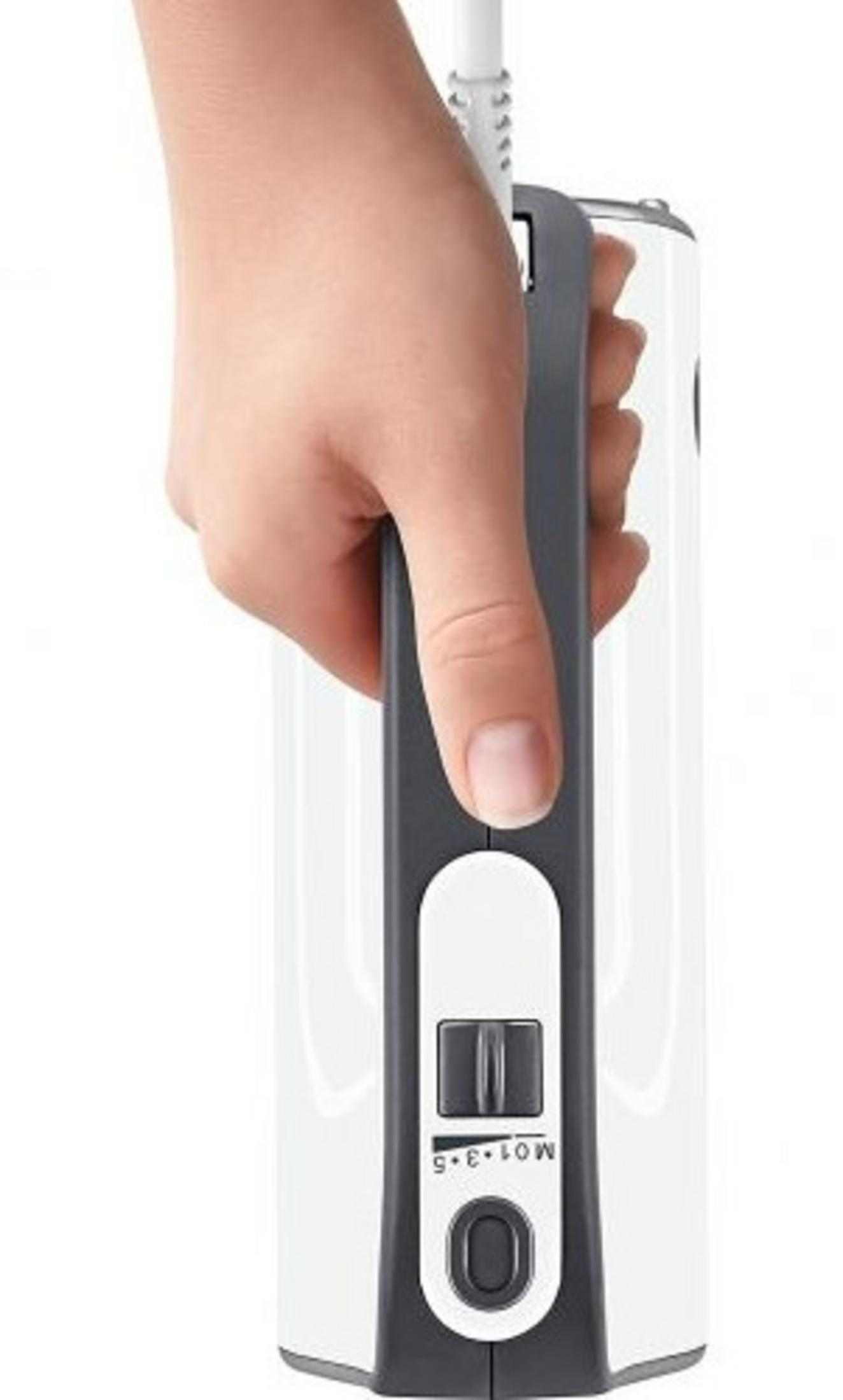 Dłoń trzyma biało-szare urządzenie elektryczne. U góry biały przewód. Urządzenie posiada pokrętło i przycisk.