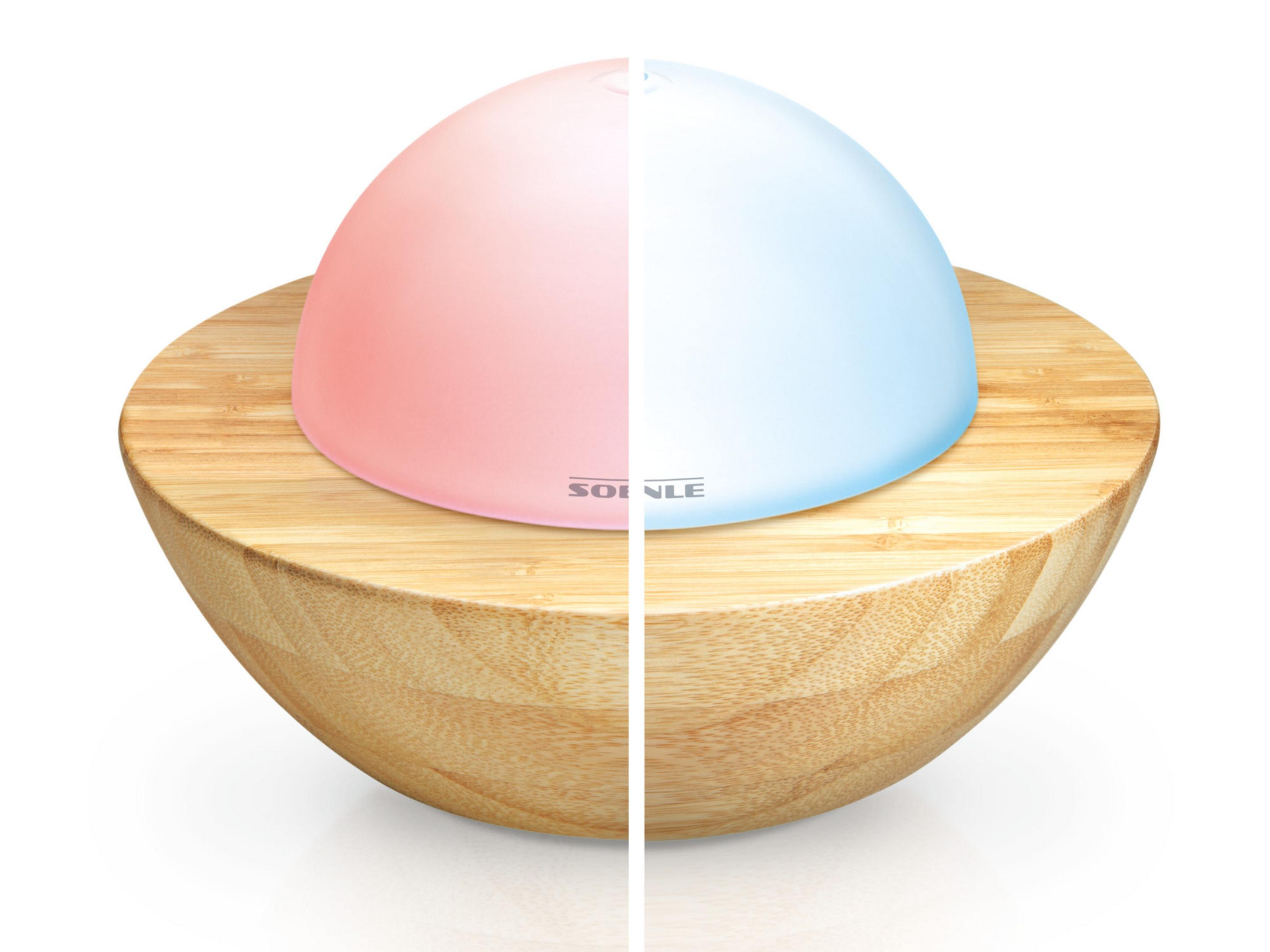 Dwukolorowa lampa w drewnianej misce. Jedna połowa różowa, druga niebieska. Misa jest jasnobrązowa.