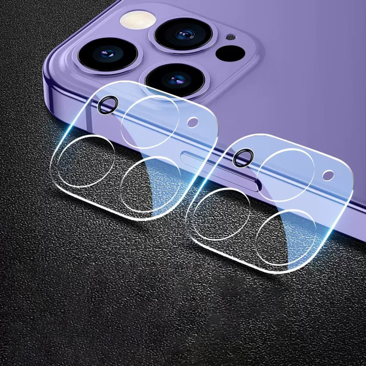 Teléfono púrpura con lentes de cámara, dos protectores de lente transparentes y una superficie negra texturizada.