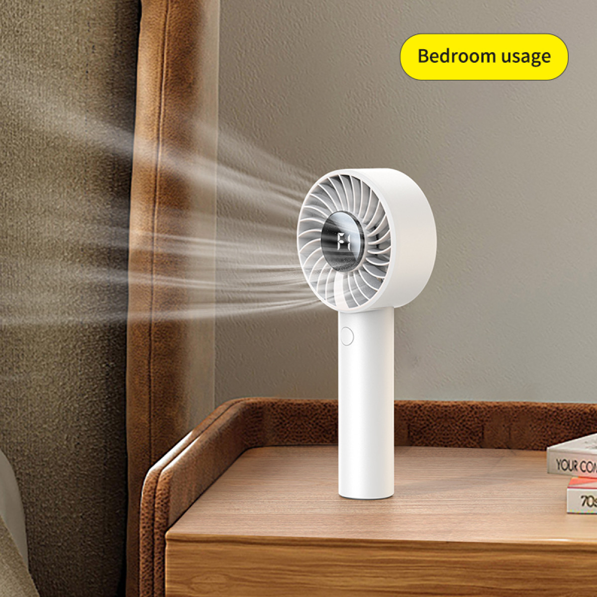 Biały przenośny wentylator stoi na drewnianej szafce nocnej. Wentylator wieje powietrzem. Dymek mówi 'Użycie w sypialni'.
