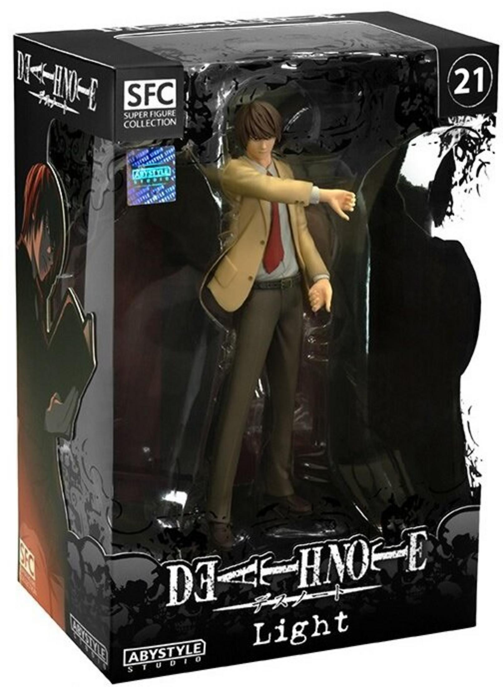Figurka Light Yagami w pudełku. Ma beżową kurtkę, czerwony krawat i ciemne spodnie. Na pudełku jest logo Death Note.