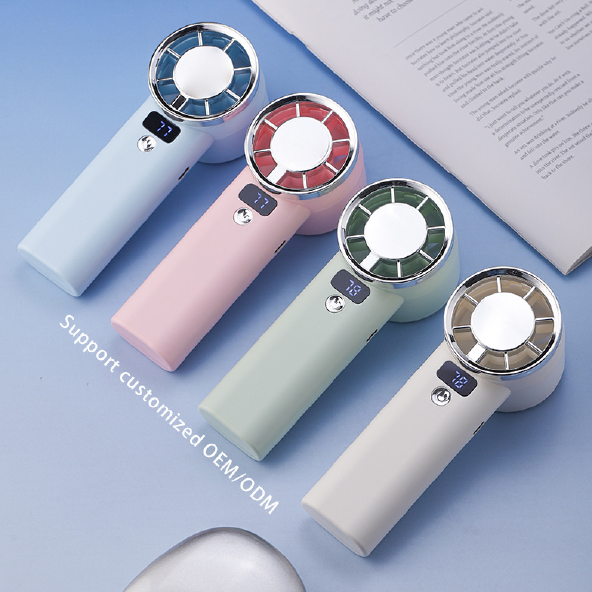 Cztery kolorowe wentylatory ręczne z wyświetlaczami cyfrowymi. Niebieskie, różowe, zielone i białe wentylatory są ułożone po przekątnej.