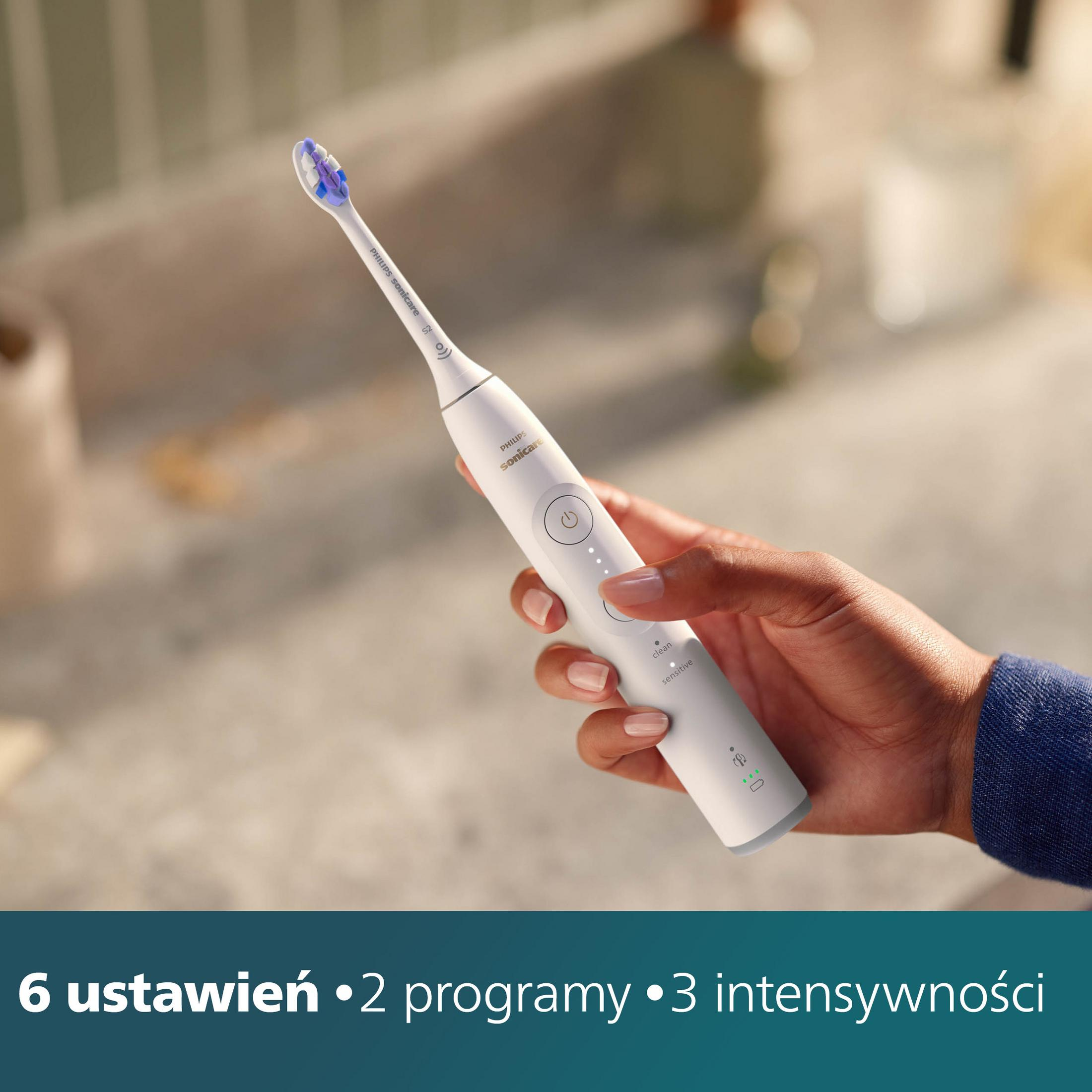 Eine Hand hält eine weiße Philips Sonicare Zahnbürste. Der Bürstenkopf ist blau. Der Text zeigt Einstellungen und Programme an.