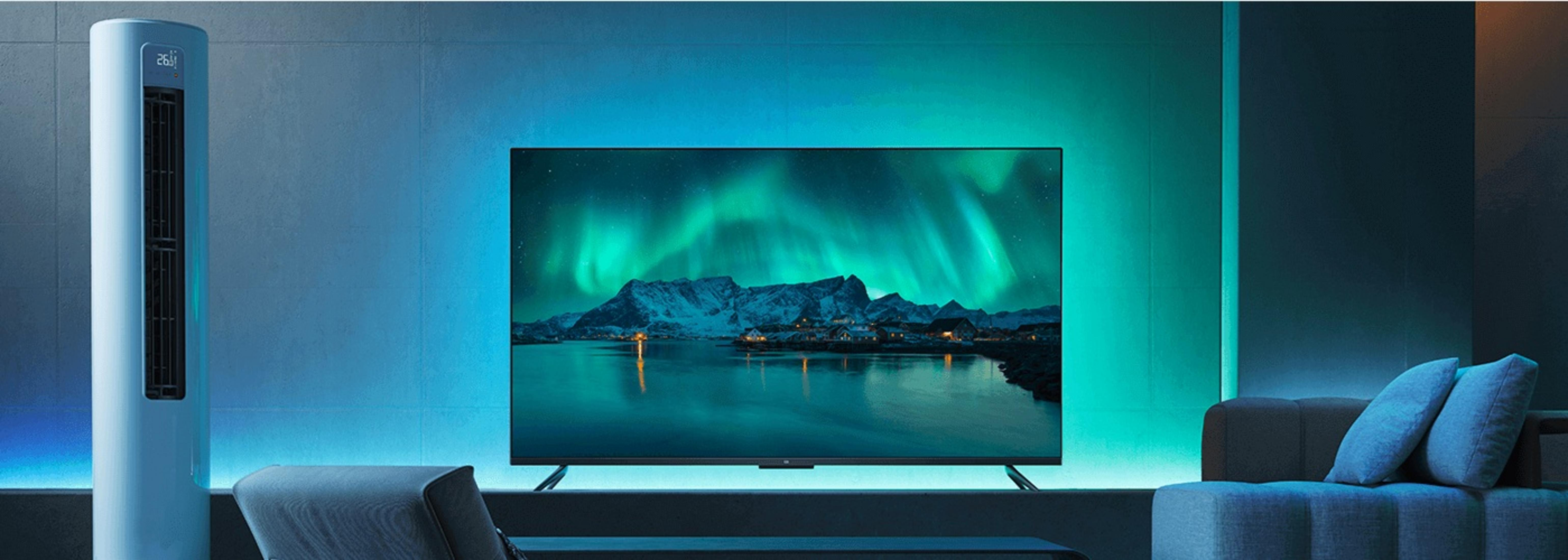 Bir TV, karlı bir dağ silsilesinin üzerinde kuzey ışıklarını gösteriyor. Odada beyaz bir hava temizleyici ve gri bir kanepe var.