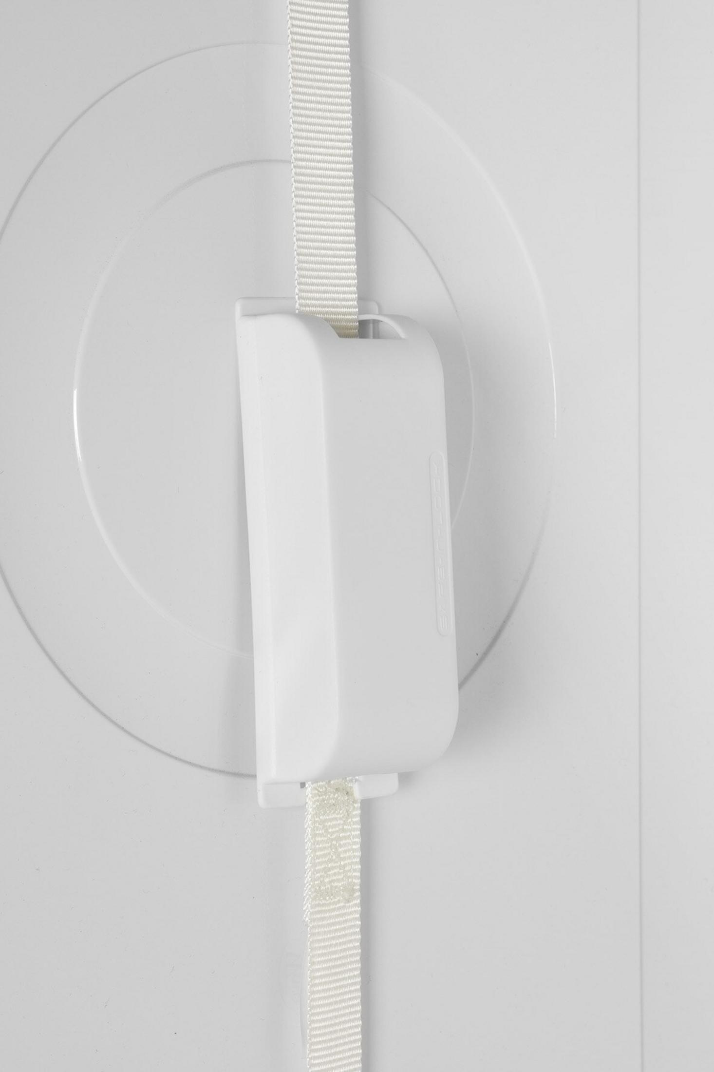 Een wit object met een witte band is bevestigd aan een wit oppervlak. De band gaat door het object.