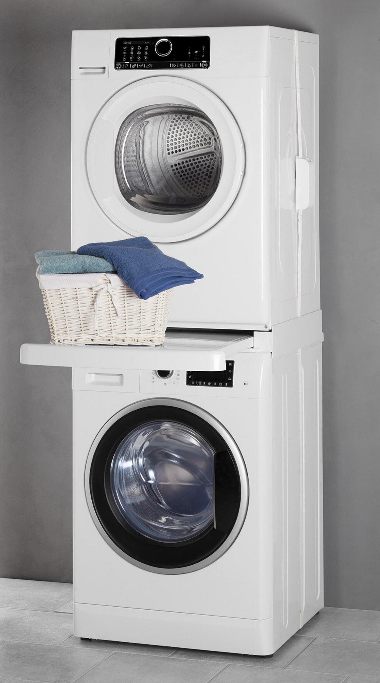 Een witte stapel wasmachine en droger, met een mand met handdoeken erbovenop. Grijze muur en betegelde vloer.