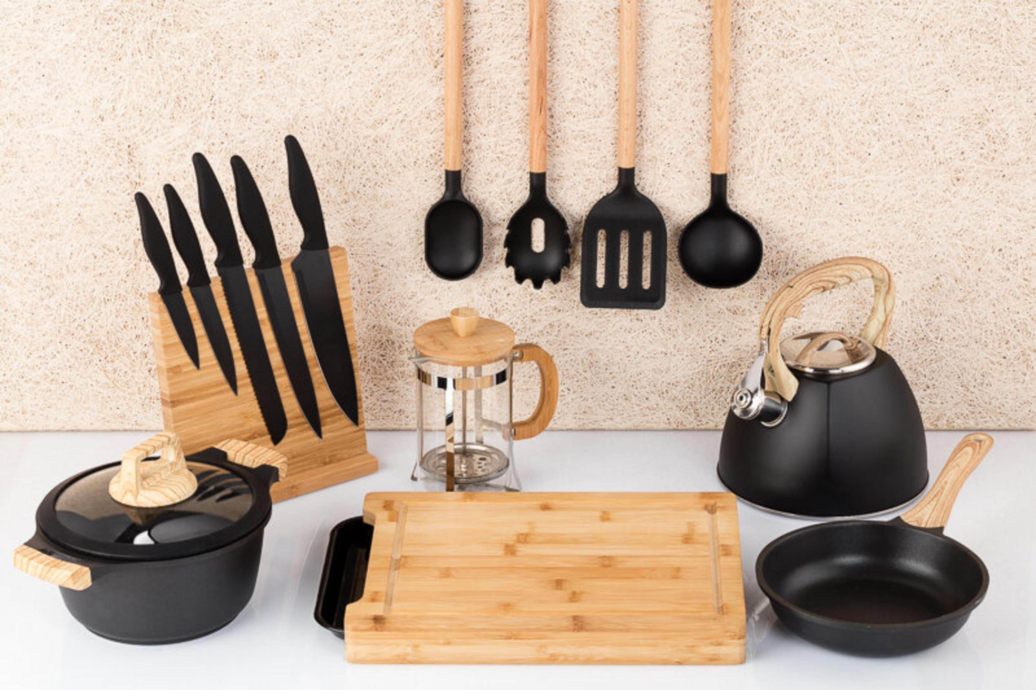 Utensilios de cocina: cuchillos, olla, prensa francesa, tetera, sartenes, tabla de cortar y cucharas.