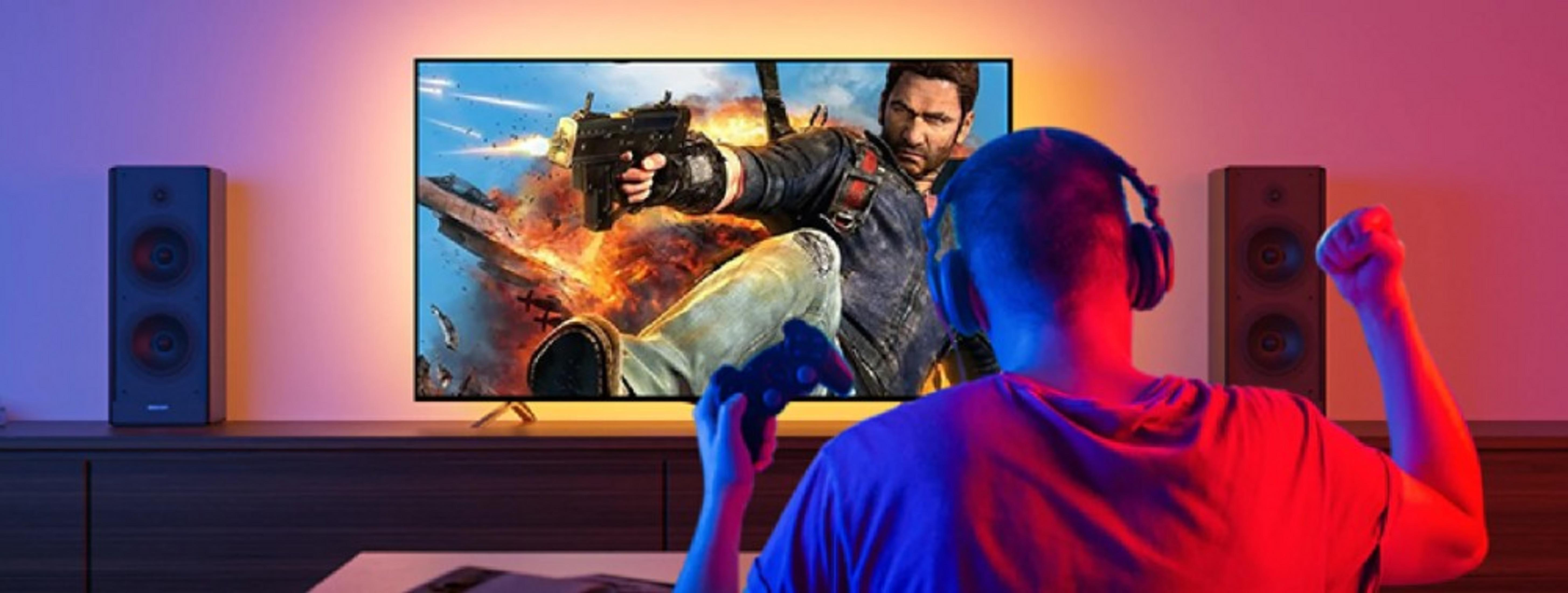 Una persona con le cuffie gioca a un gioco in TV. La TV mostra un gioco sparatutto. Ci sono altoparlanti su entrambi i lati.