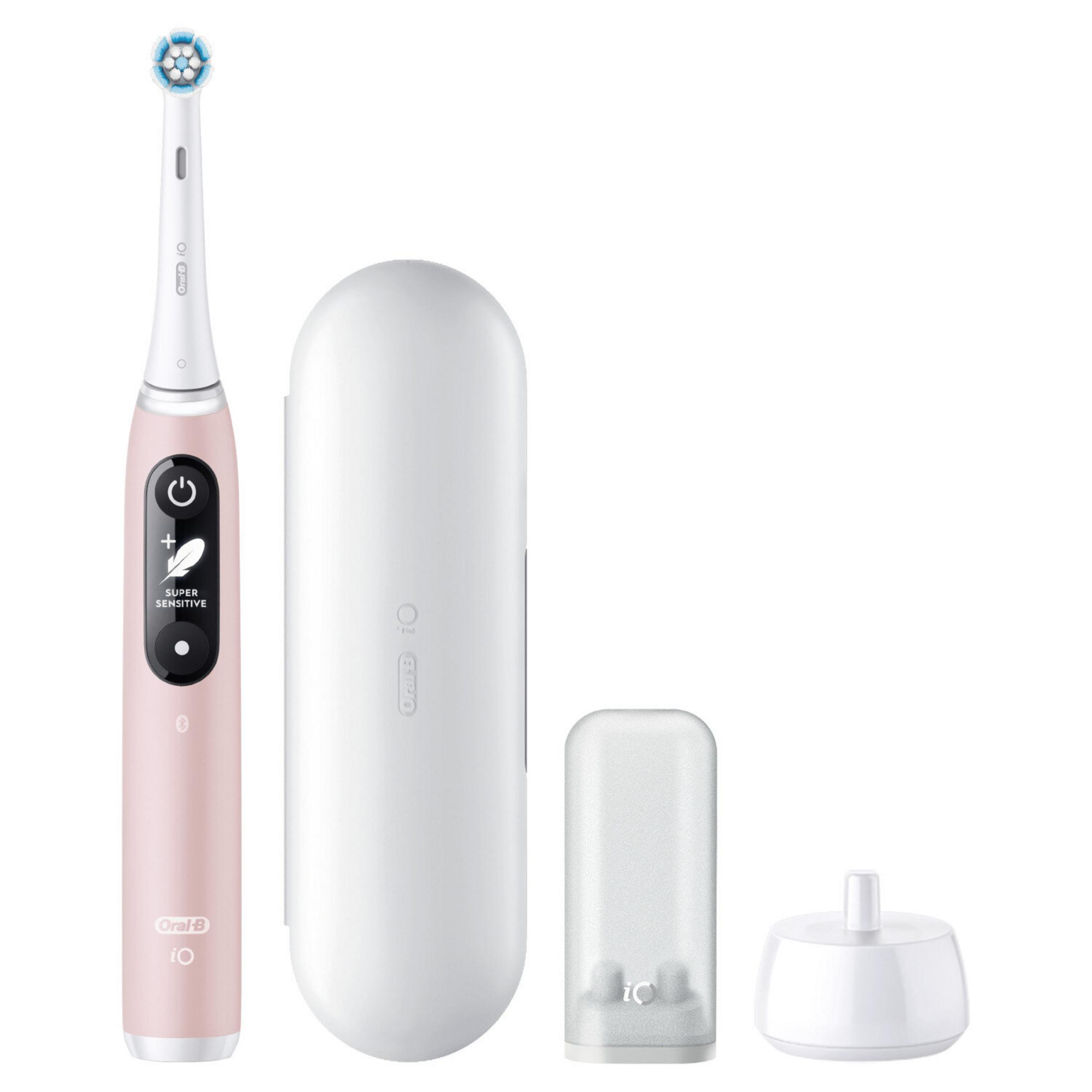Różowa elektryczna szczoteczka do zębów Oral-B iO, etui podróżne, osłona główki szczoteczki i stacja ładująca na białym tle.