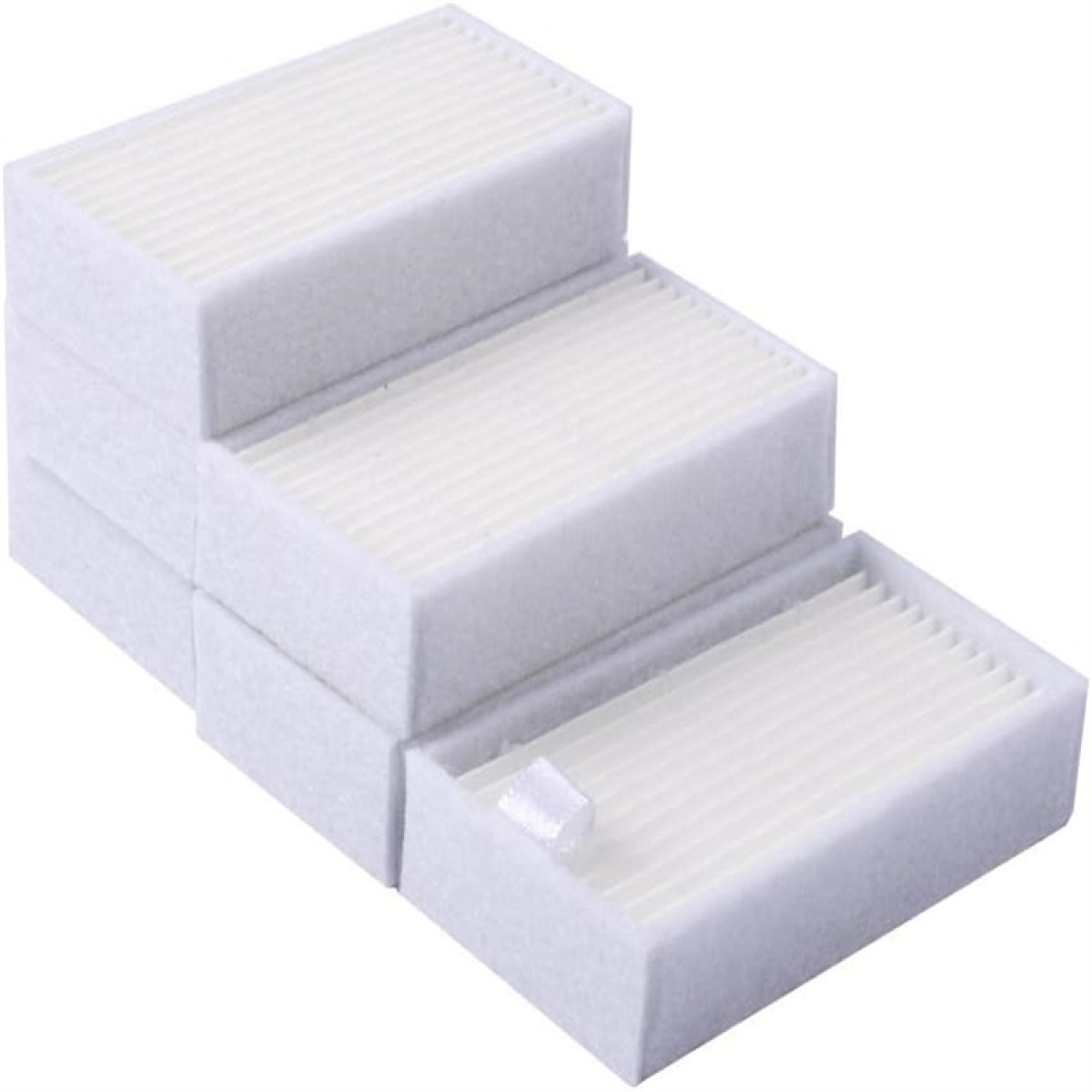 Kilka ułożonych w stos białych filtrów powietrza jest wyświetlanych pod kątem, ujawniając ich pofałdowaną strukturę wewnętrzną. Mały kwadrat białego materiału leży na jednym.