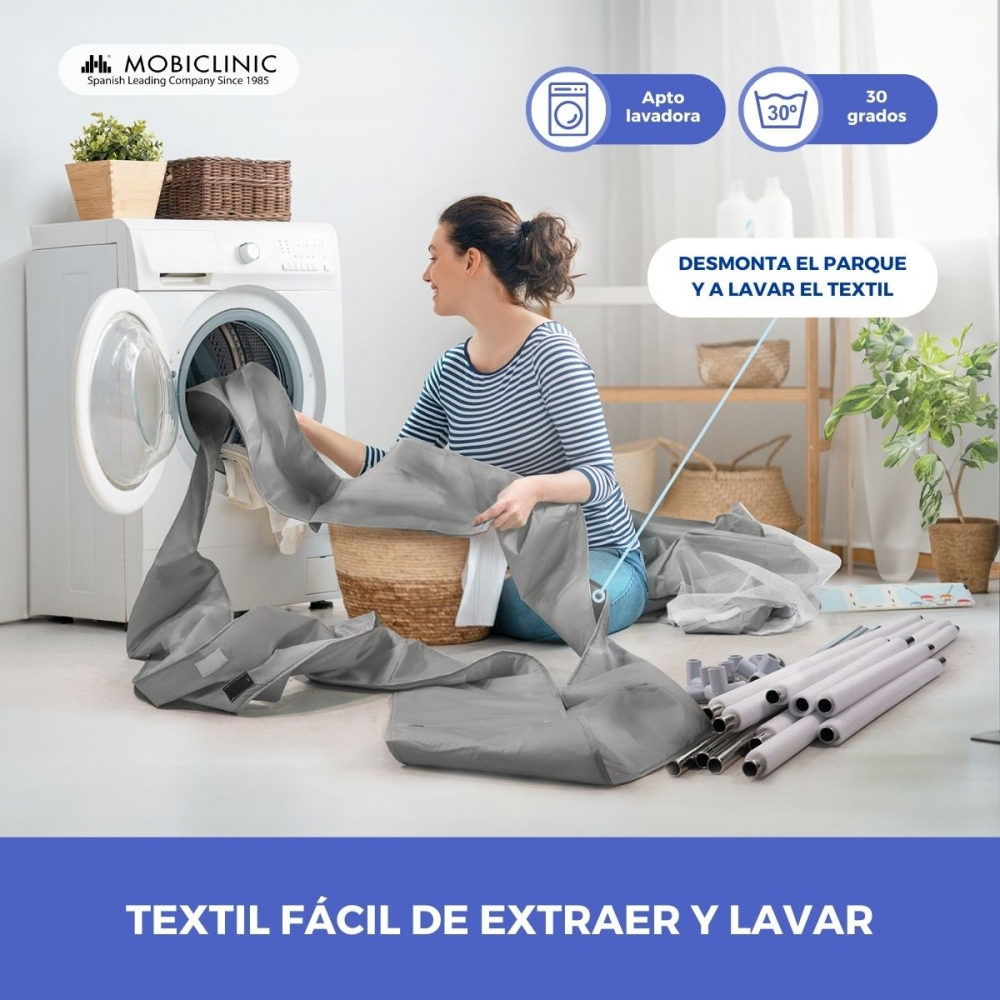Una mujer carga una lavadora con tela gris. Los símbolos de lavado indican lavado a máquina. El texto dice: "textil fácil de quitar y lavar."