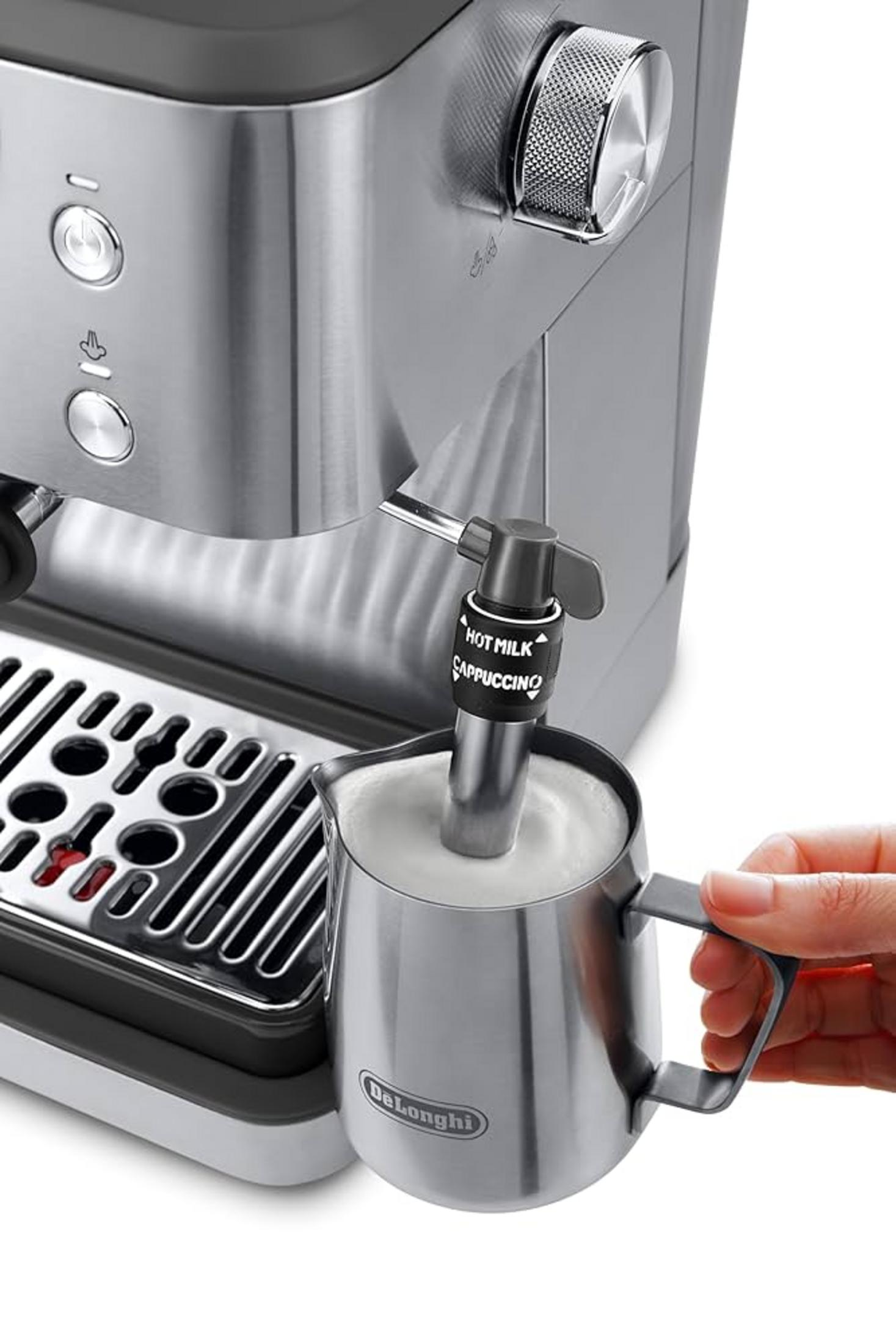 Silberne Espressomaschine mit Aufschäumkanne. Milch wird aufgeschäumt. Eine Hand hält die Kanne.