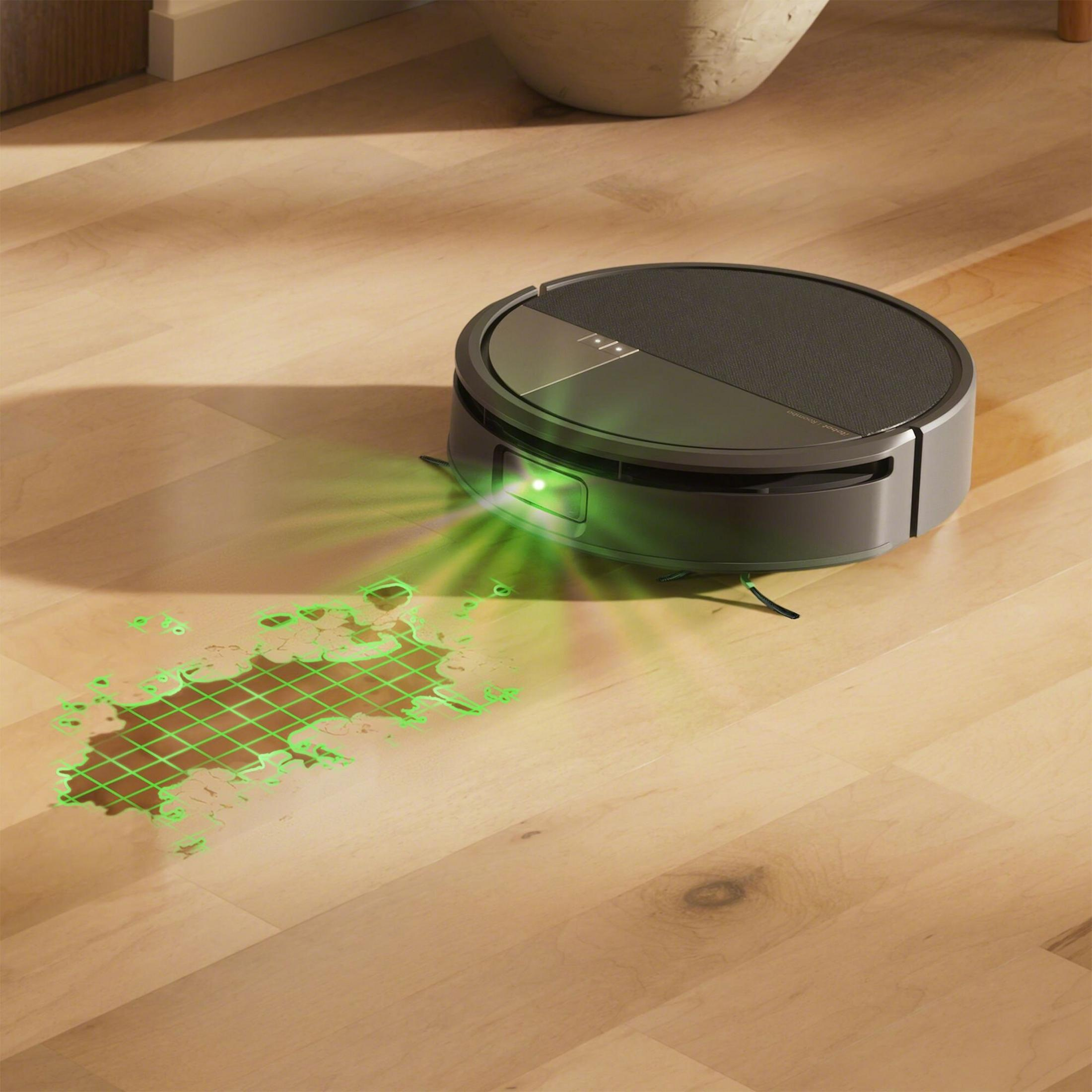 Una aspiradora robótica emitiendo luz verde sobre un piso de madera. La luz delinea un derrame, sugiriendo limpieza.