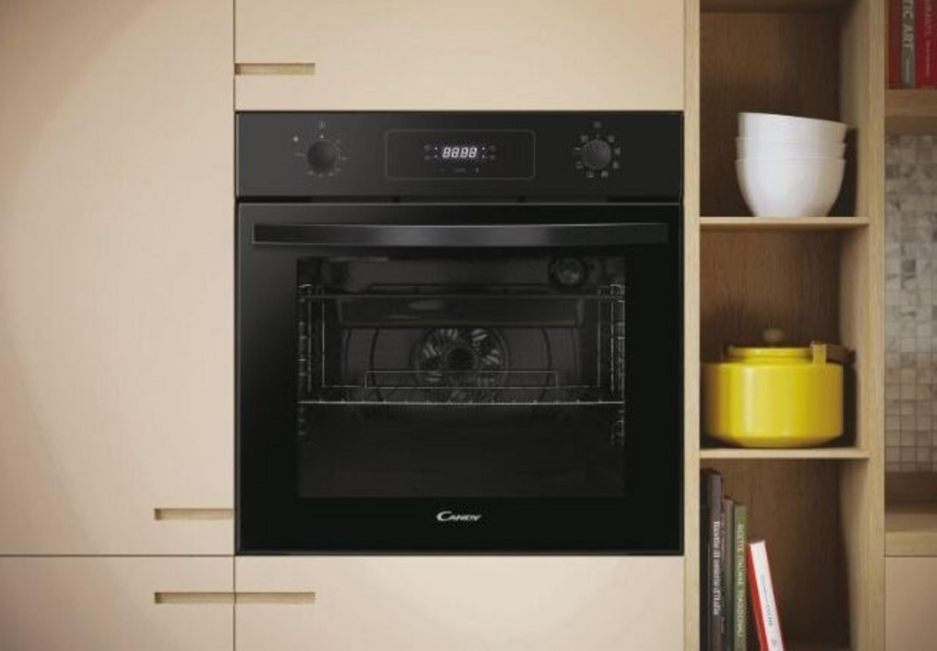 Un horno negro empotrado en un armario beige. Una estantería al lado tiene cuencos y una olla amarilla.
