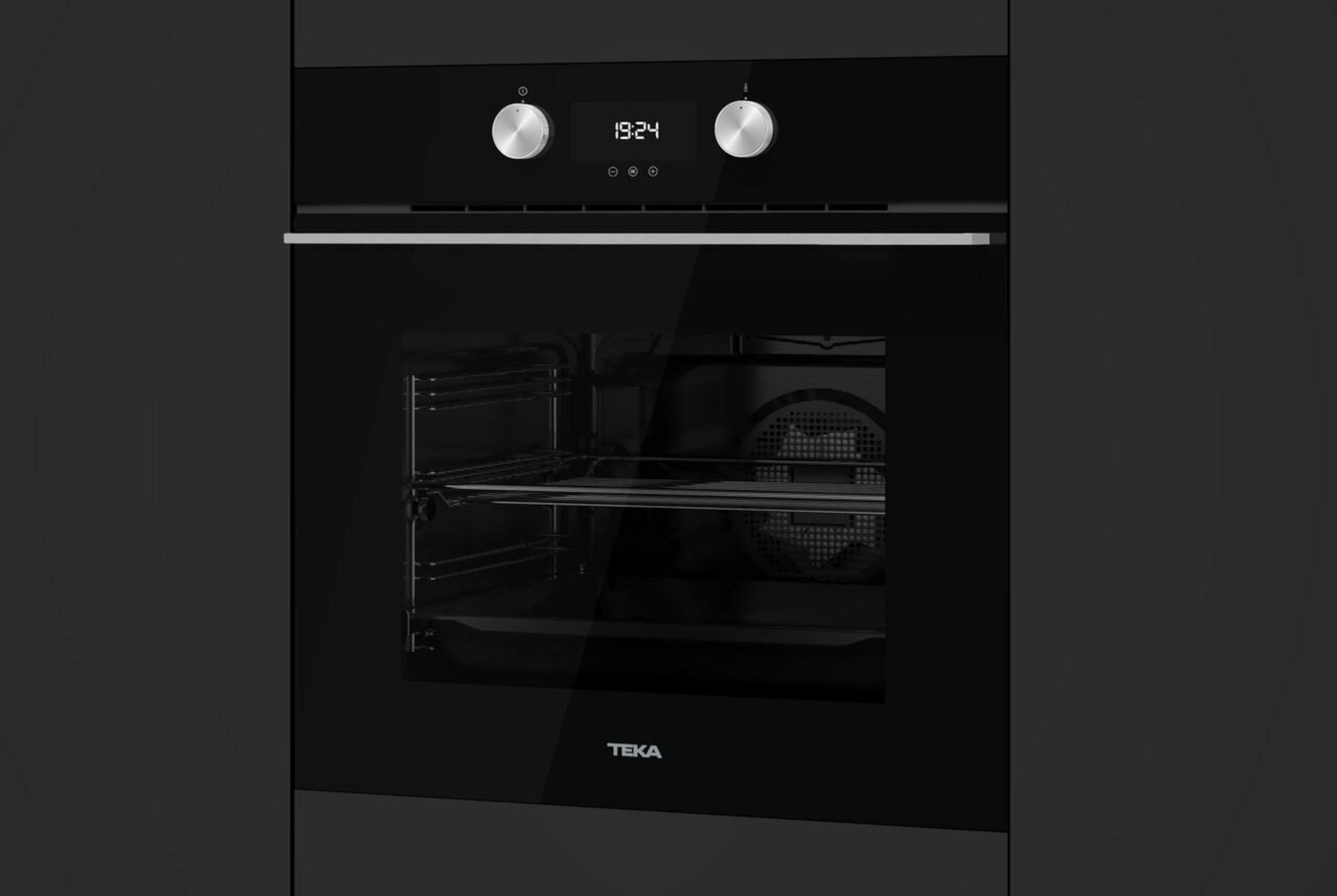Czarny piekarnik z cyfrowym zegarem pokazującym 19:24. Ma stalowe pokrętła i logo Teka.