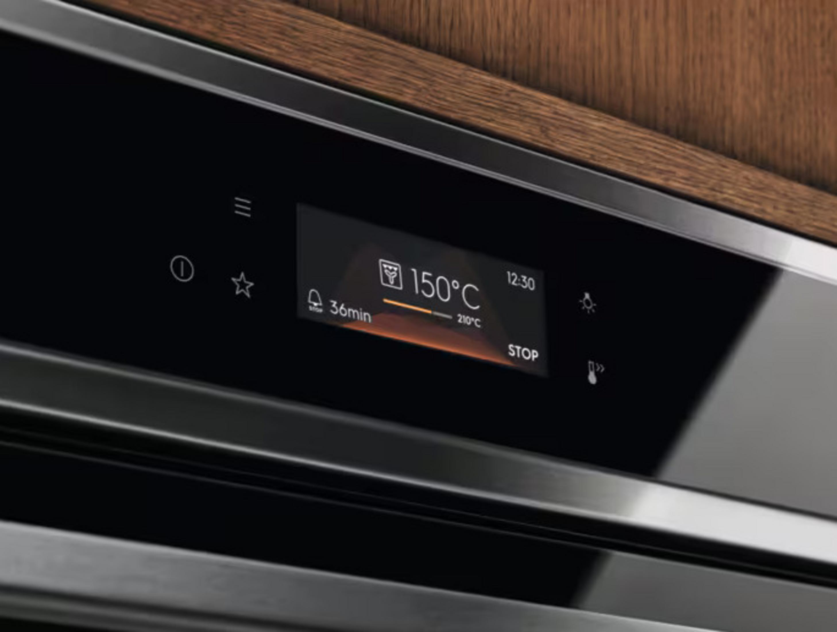 Il pannello di controllo del forno mostra 150°C, timer 36min e altre impostazioni. Pannello scuro con icone e finiture in legno.