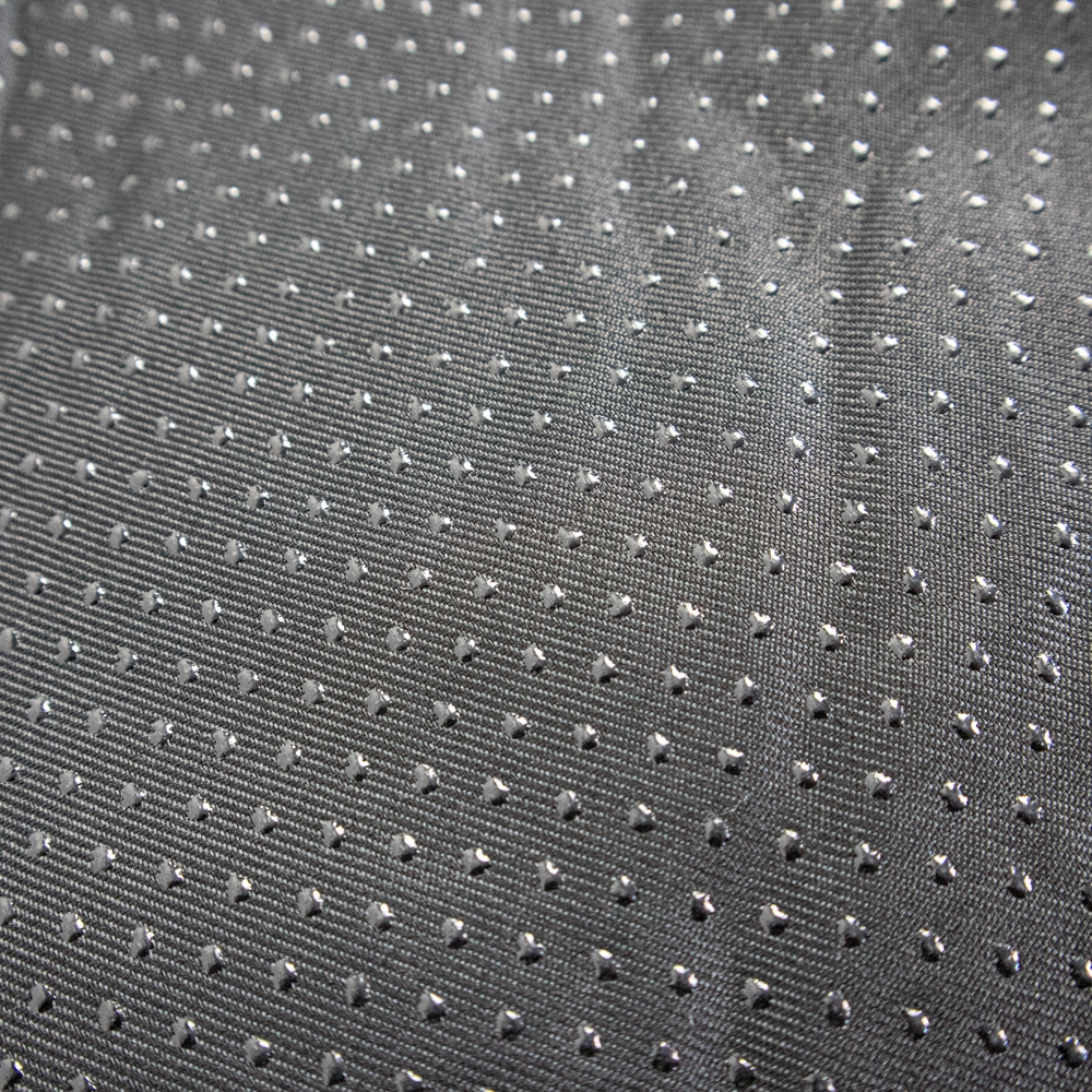 Primer plano de una tela gris con pequeños puntos en forma de diamante en filas y columnas.
