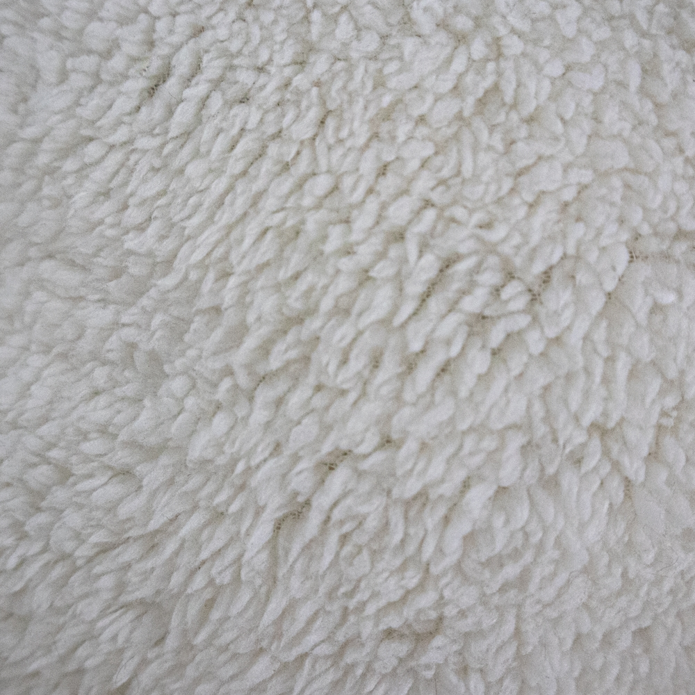 Primer plano de una tela blanca, esponjosa y texturizada. La superficie está cubierta de fibras suaves y densas.