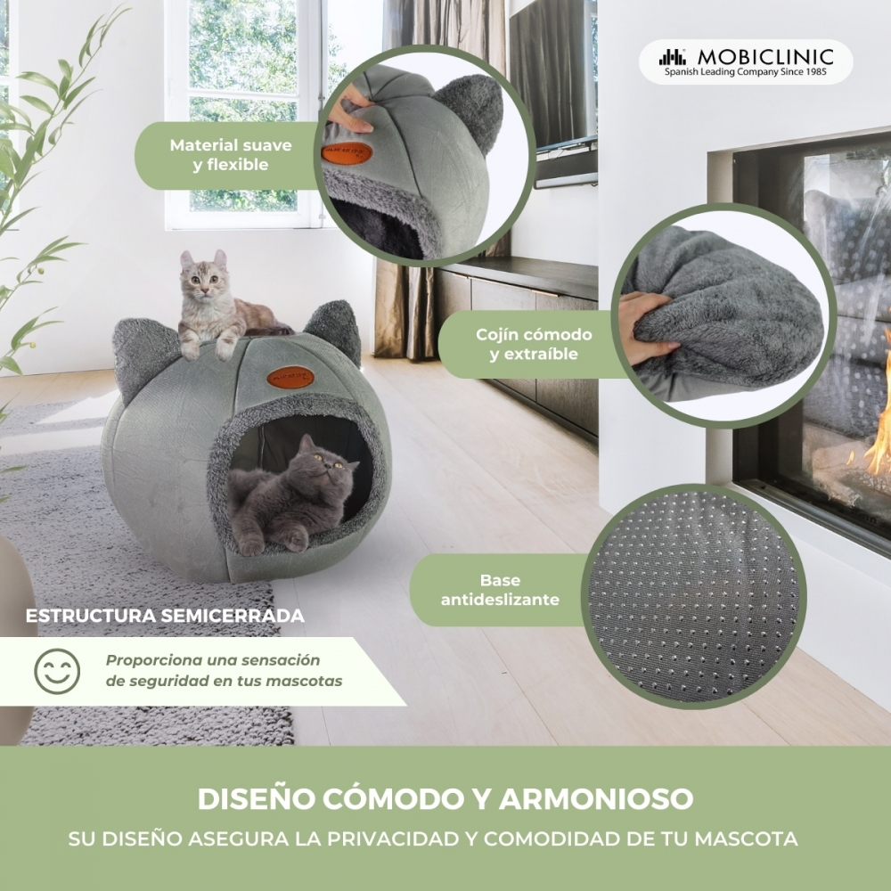 Una cama para gatos gris con lados en forma de orejas. Dos gatos están dentro o cerca de la cama. El texto detalla material suave, cojín extraíble y base antideslizante.