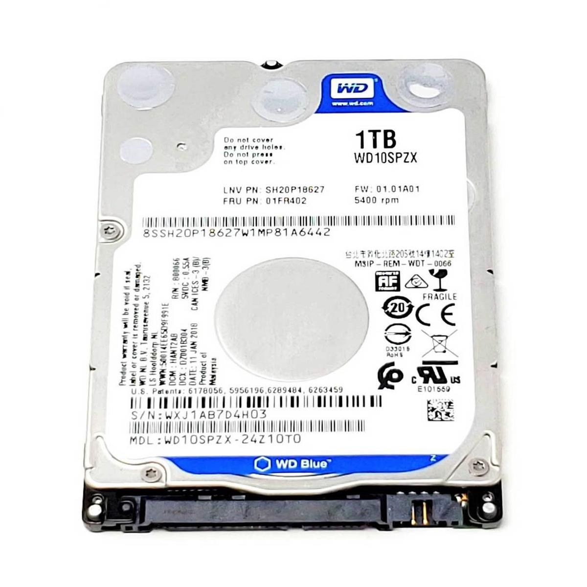 Un disco duro WD Blue de 1TB. Tiene etiquetas con texto y símbolos. La unidad es plateada y negra.