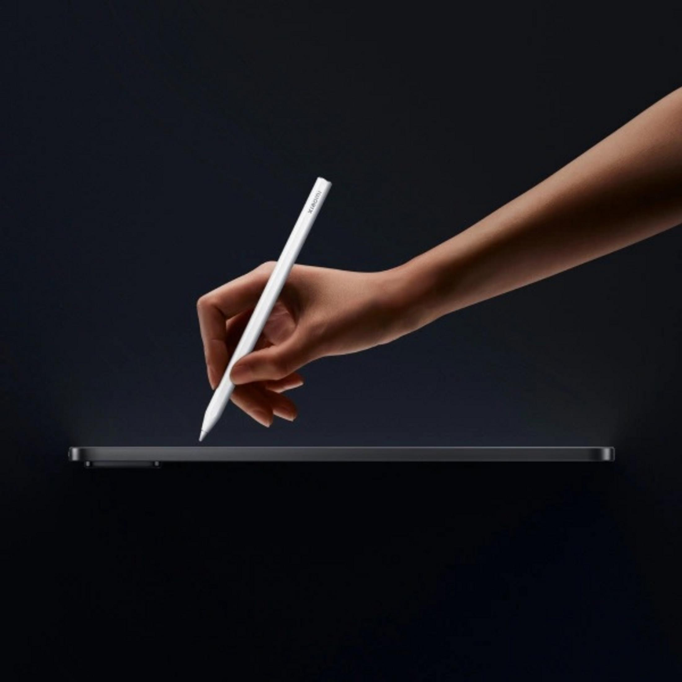 Eine Hand hält einen weißen Stift über einem dunklen Tablet. Dunkler Hintergrund.