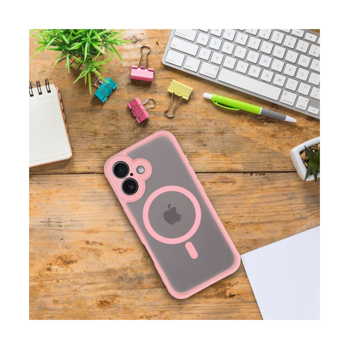 Rosa Handyhülle auf Holzschreibtisch mit Tastatur, Stiften, Clips und Pflanzen. Apple-Logo auf der Hülle sichtbar.
